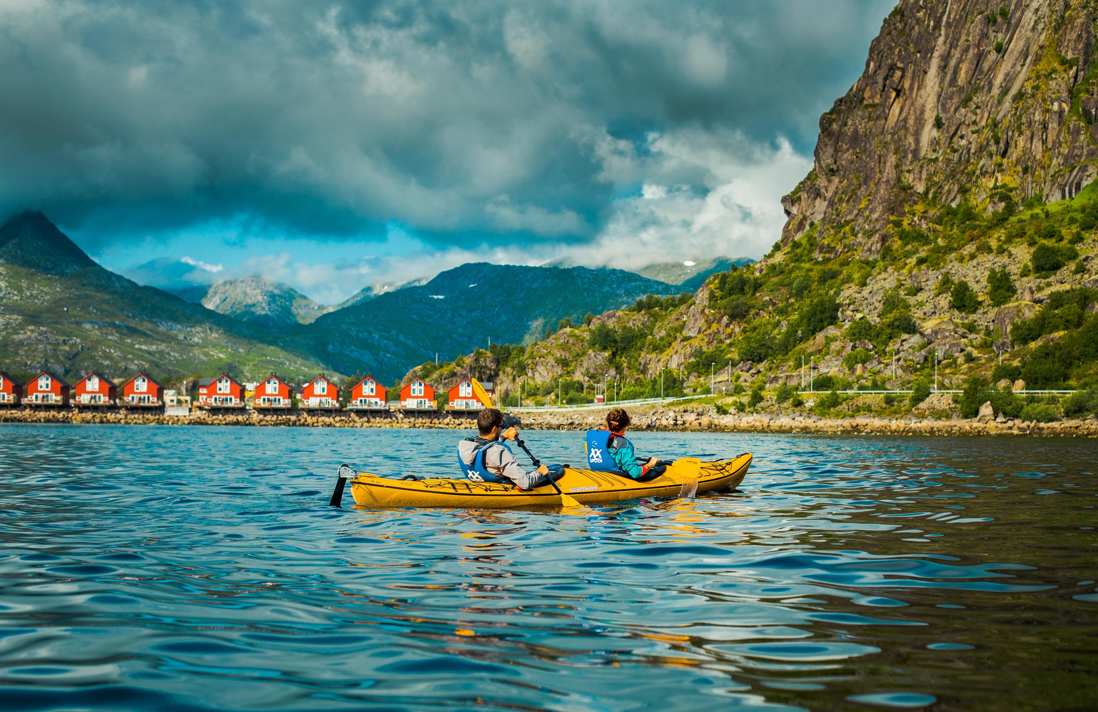 Tourists kayaking in front of red boathouse