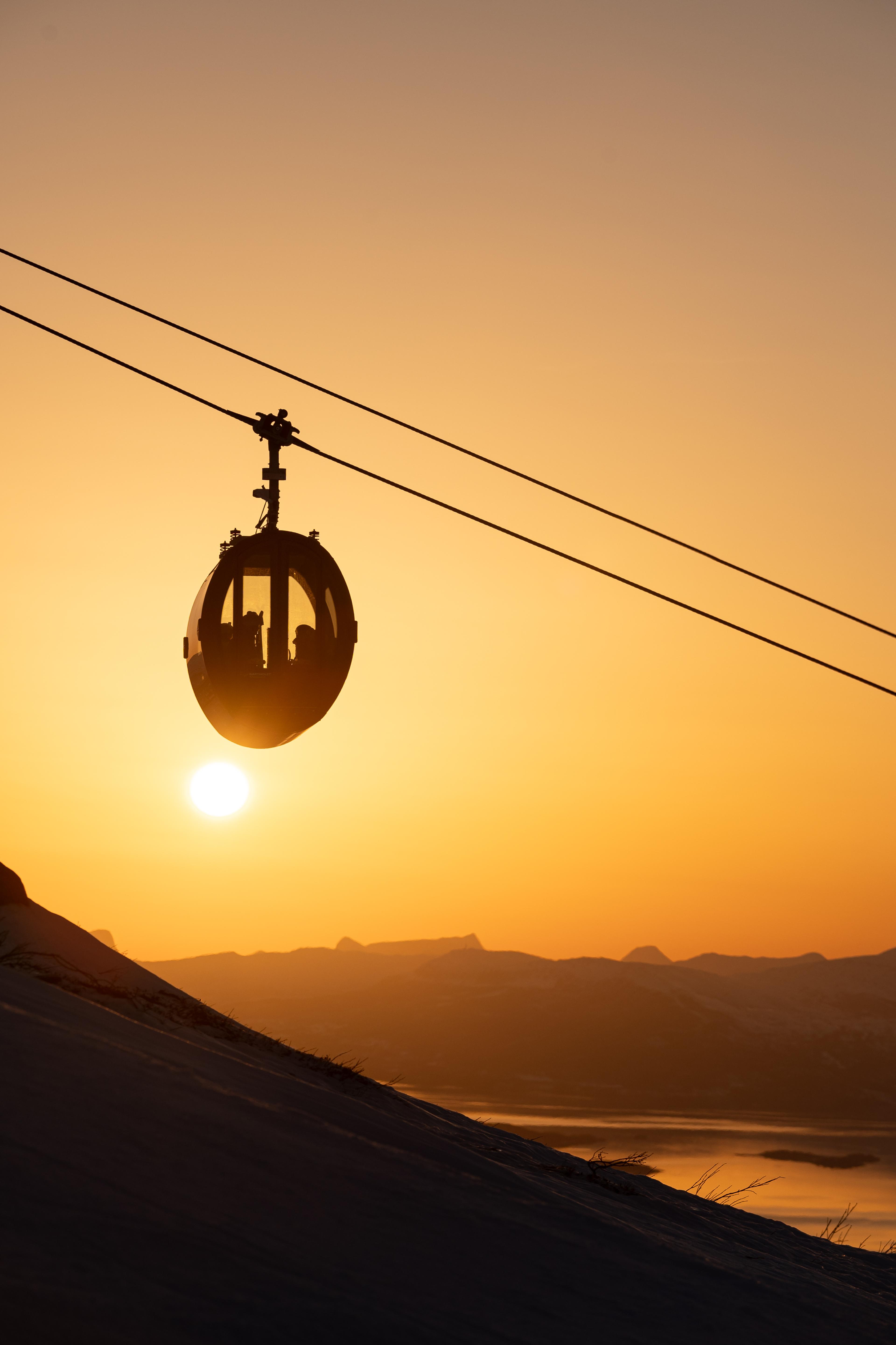Narvik Gondol i gyllent lys mot lav vintersol med fjord og fjell i bakgrunnen.