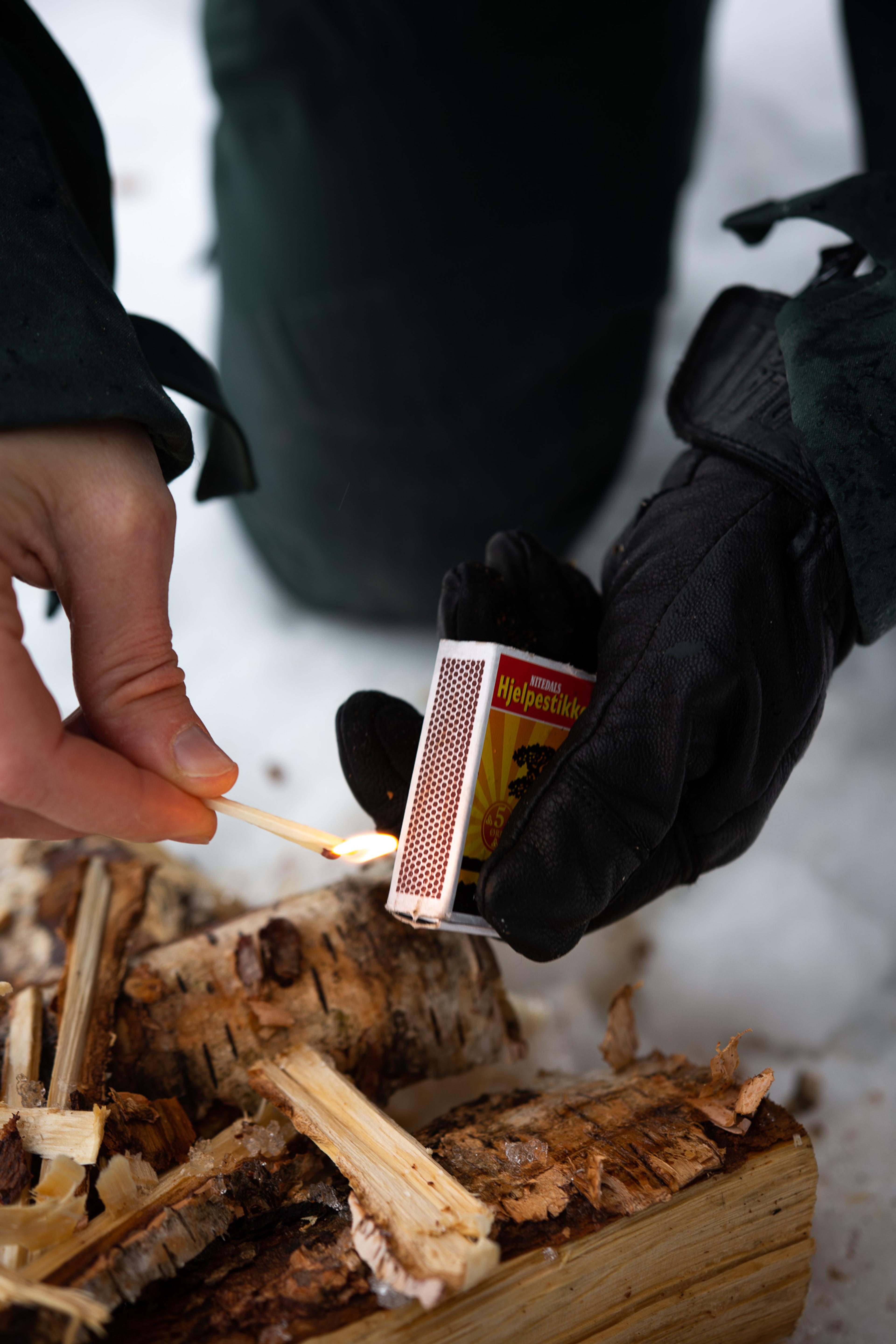 Bål i snøen tennes med fyrstikk.