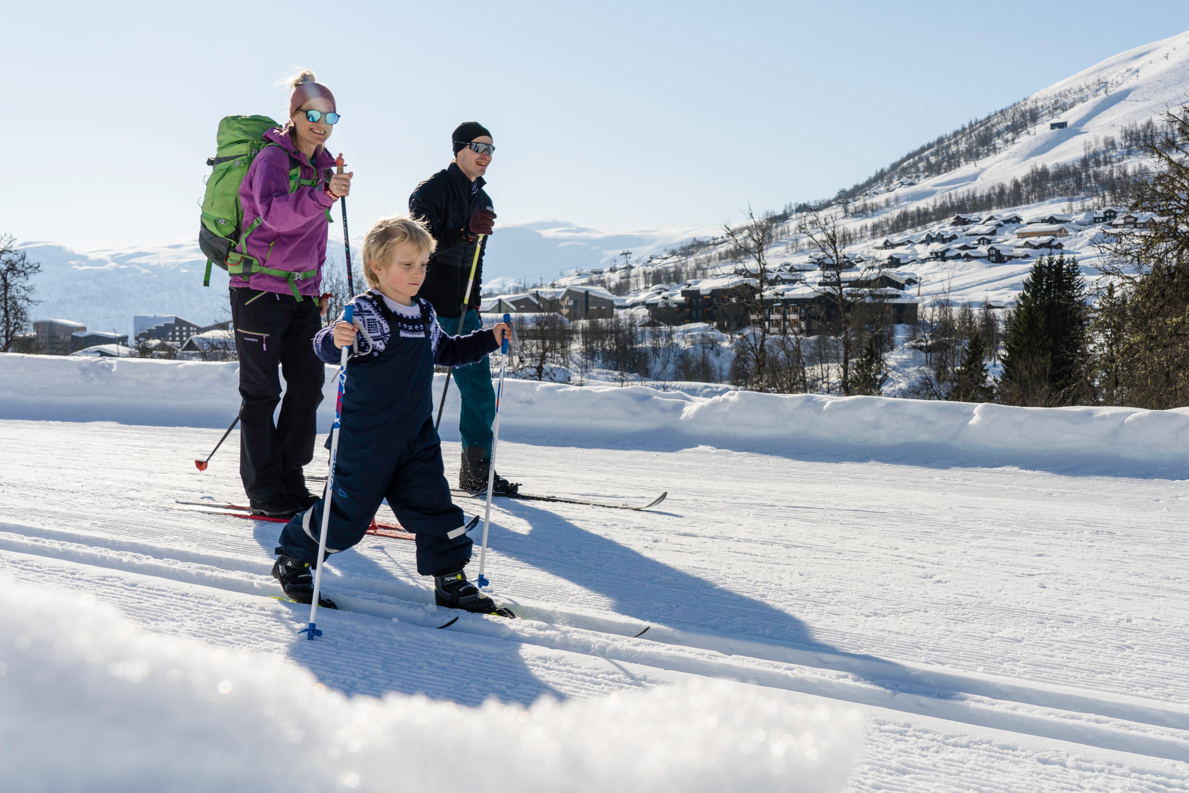 Mother, father and son on cross-country skis on freshly groomed slopes.