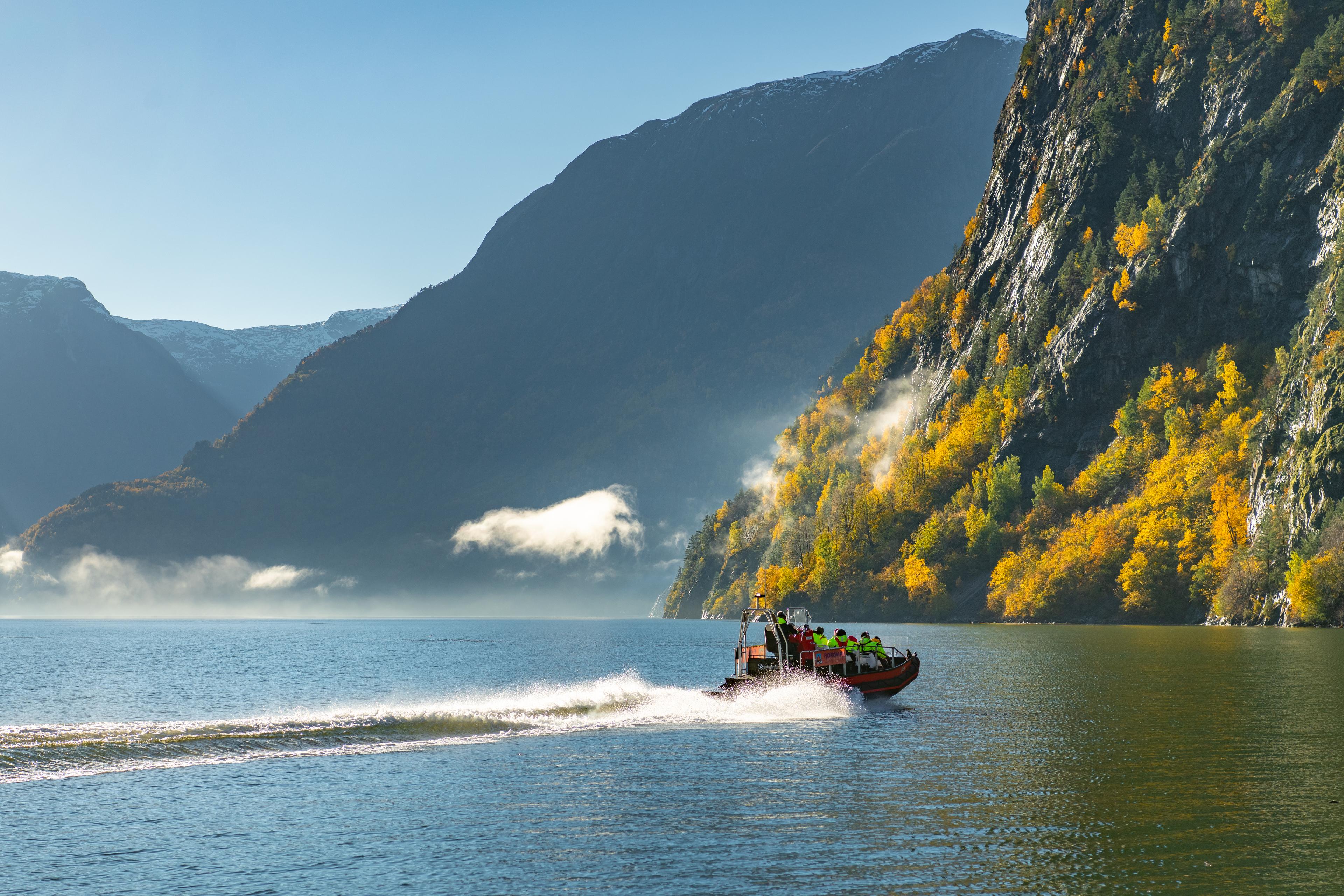 Ein RIB med passasjerar susar gjennom fjorden ein vakker haustdag.