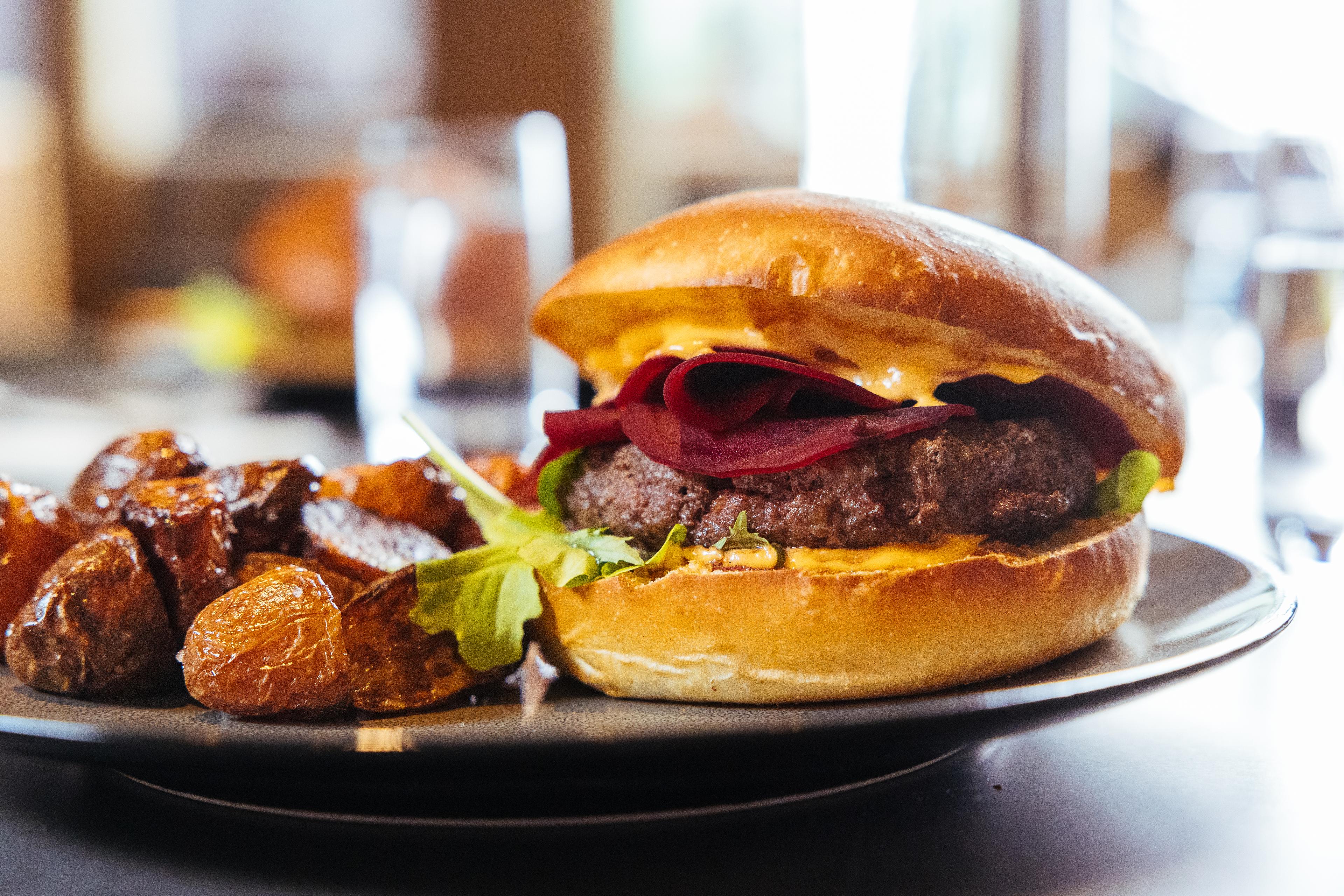 Tallerken med burger og stekte poteter på restaurant.