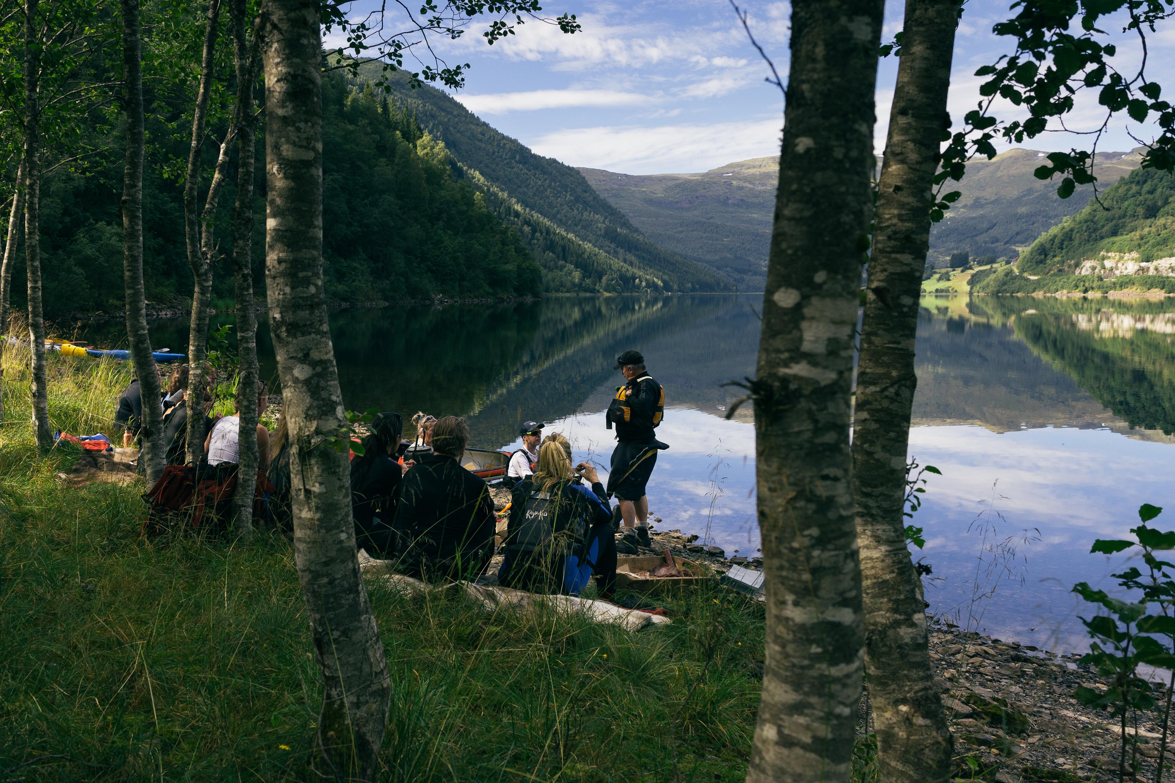 a group of people sit and look out over a lake