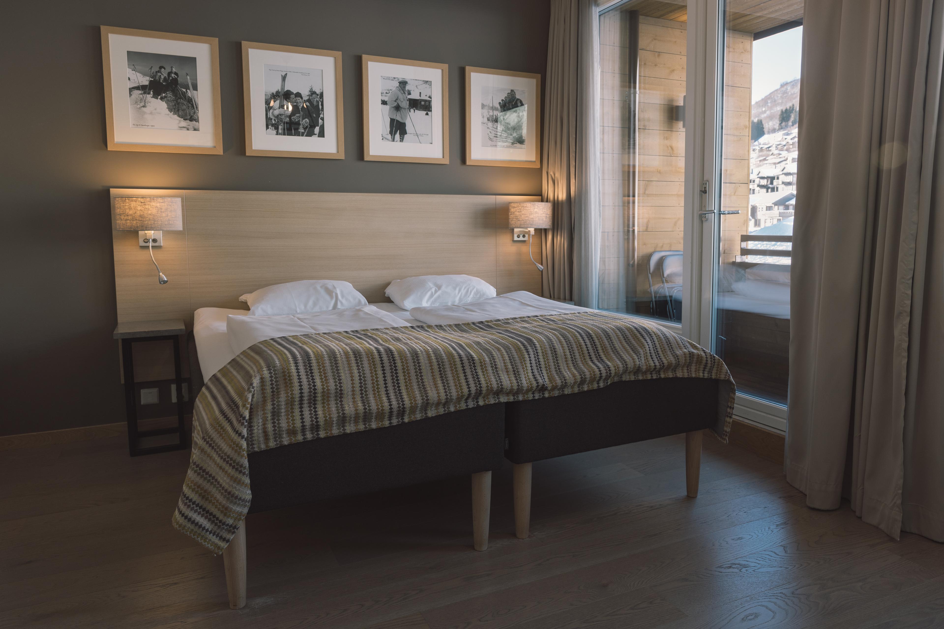 Interior of a hotel room at Myrkdalen Hotel. Double bed by a balcony filled with snow.