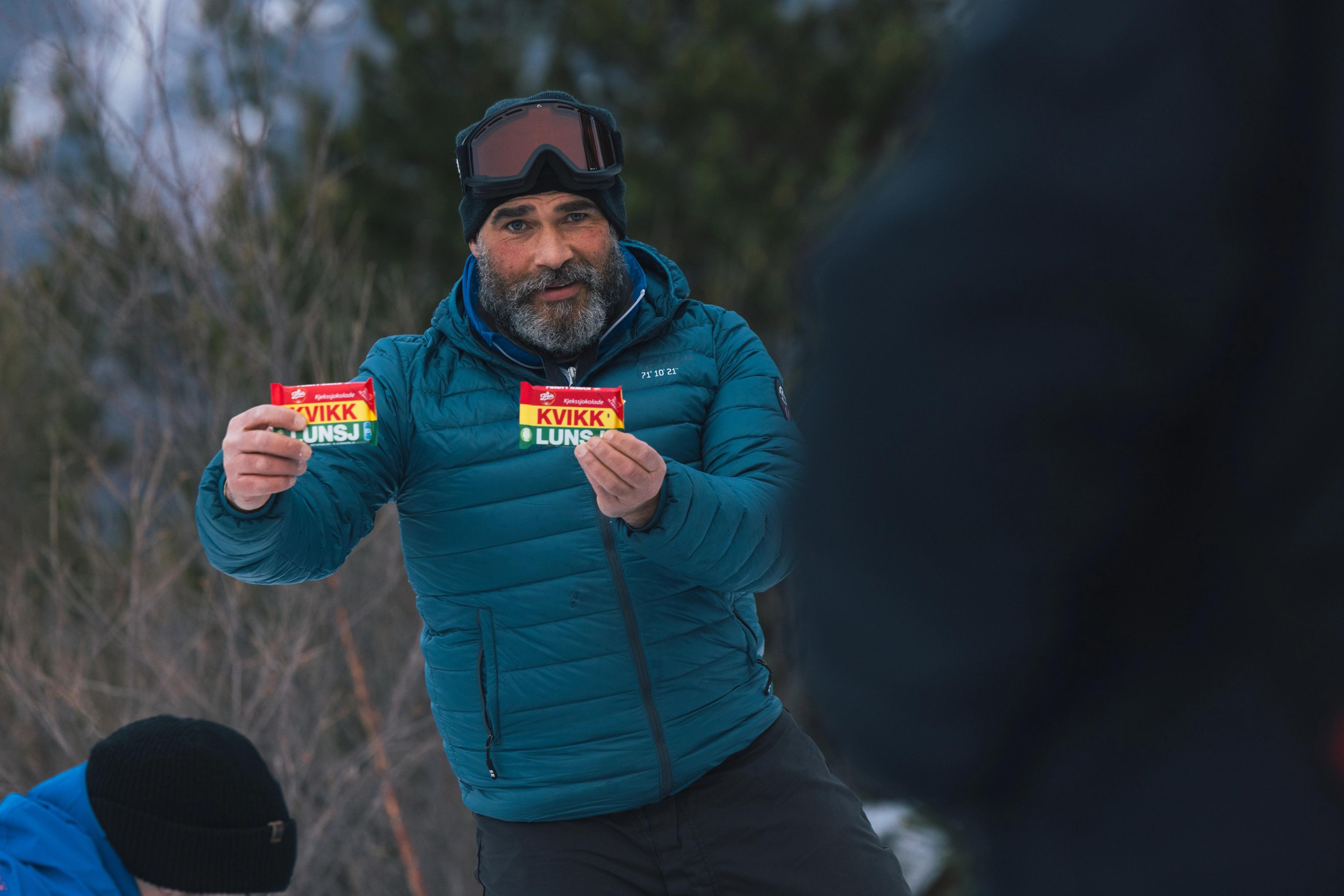  A man in winter clothes holds up two Kvikk Lunsj chocolates.