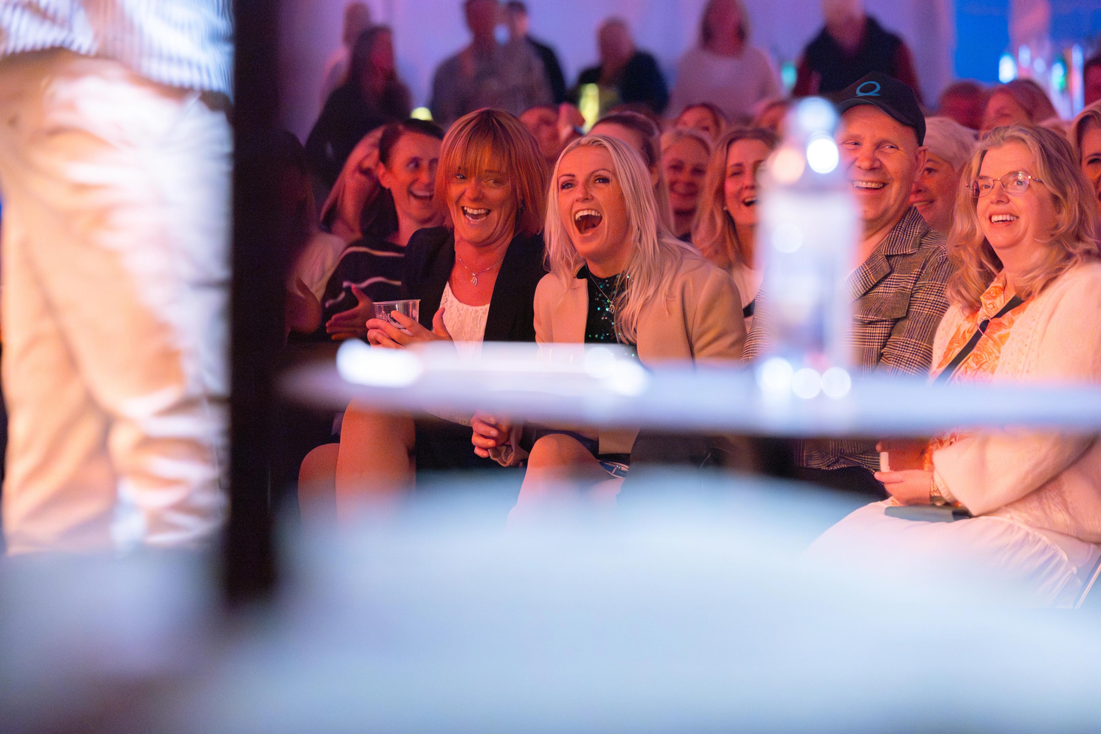 Publikum som ler av noen på en scene