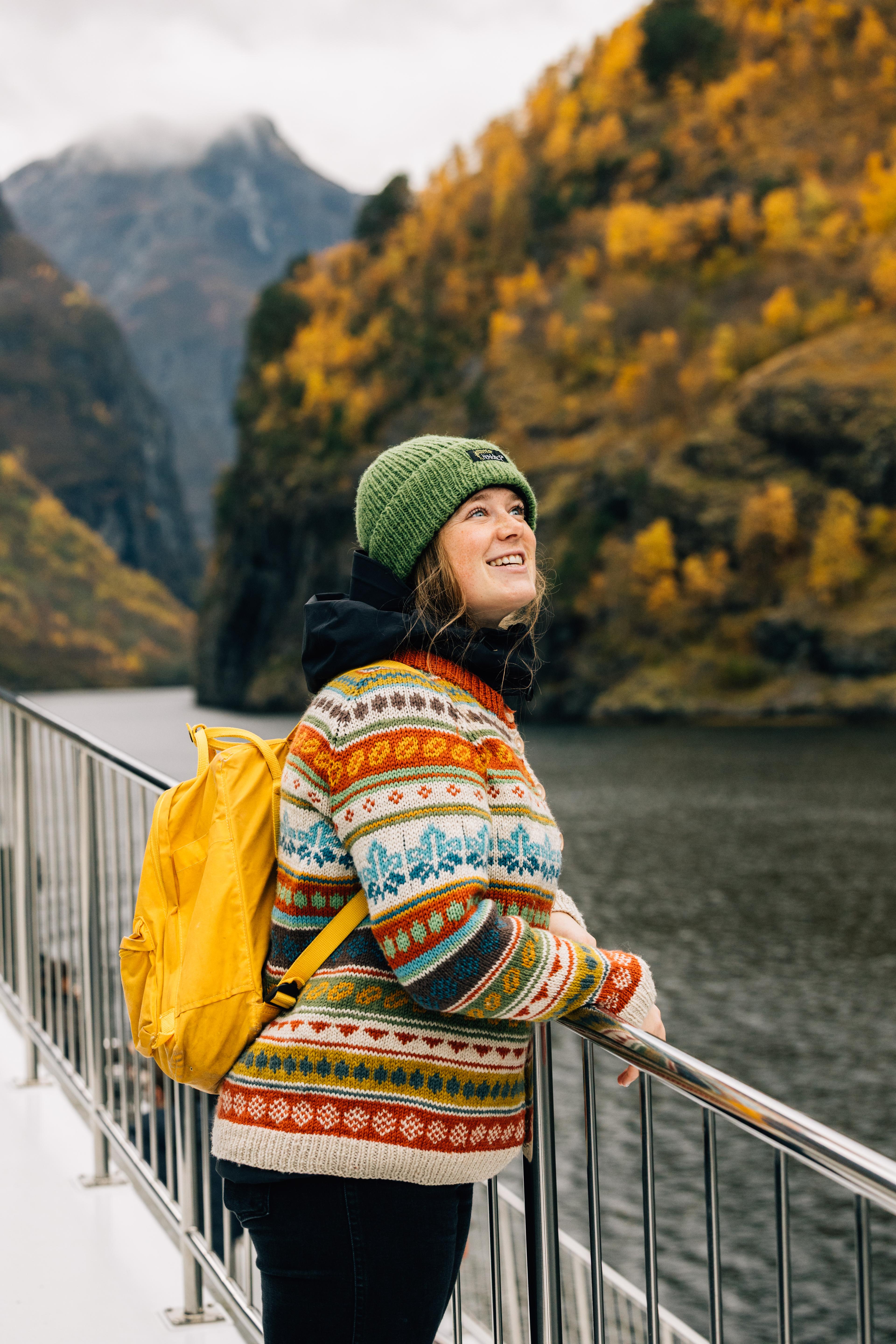 A woman on the boat in the Nærøyfjord. The mountains in the background are dressed in autumn colours.