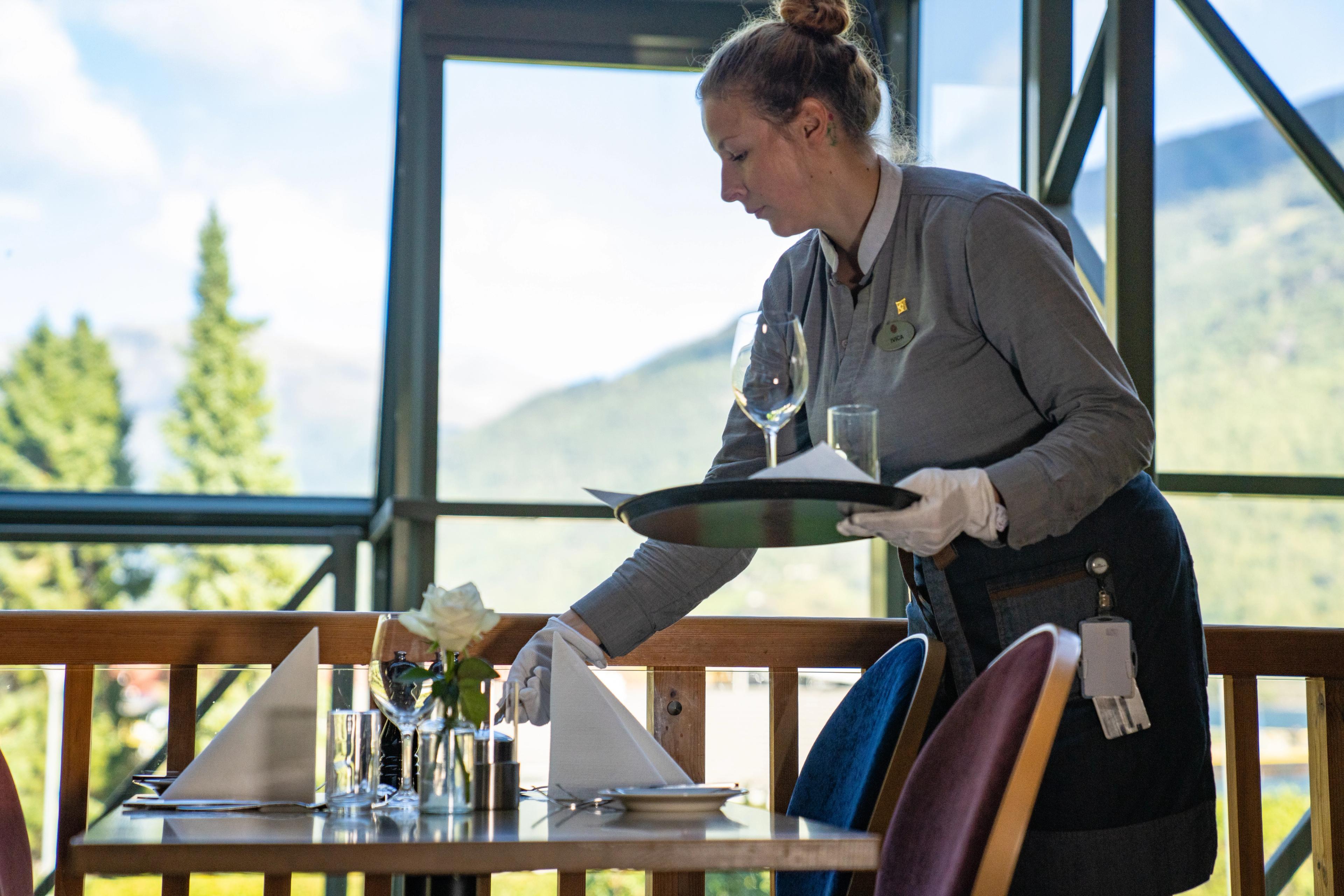 A waiter places a glass on a table in restaurant Arven. 