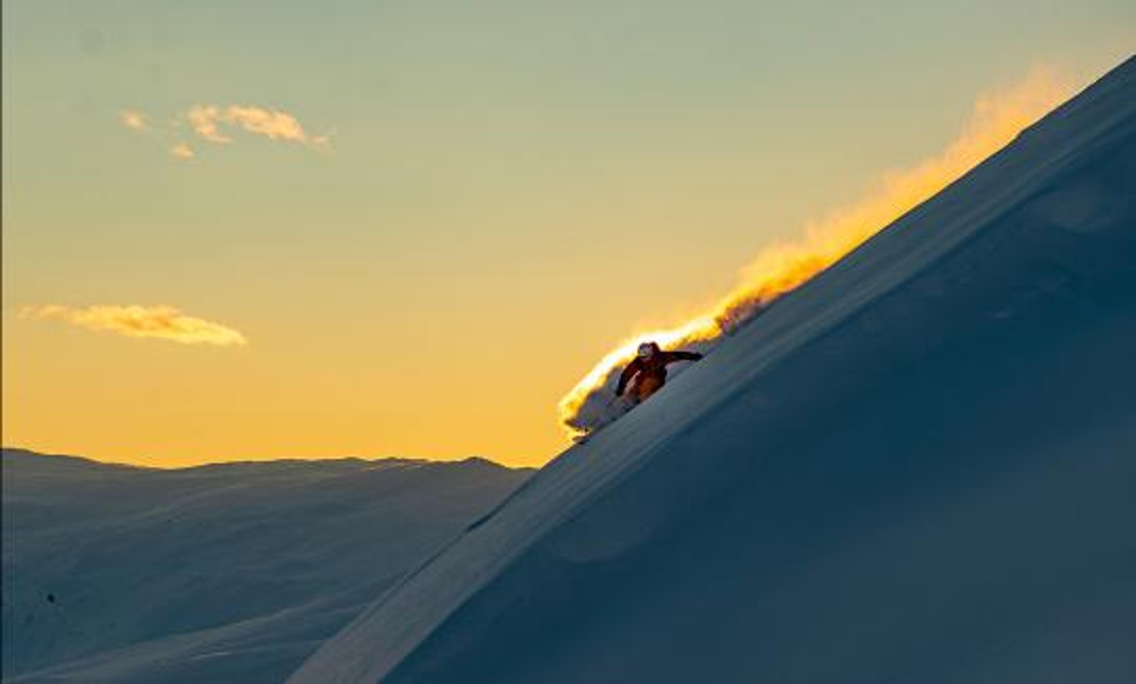 Frikjører står ned bratt fjellside i solnedgang.