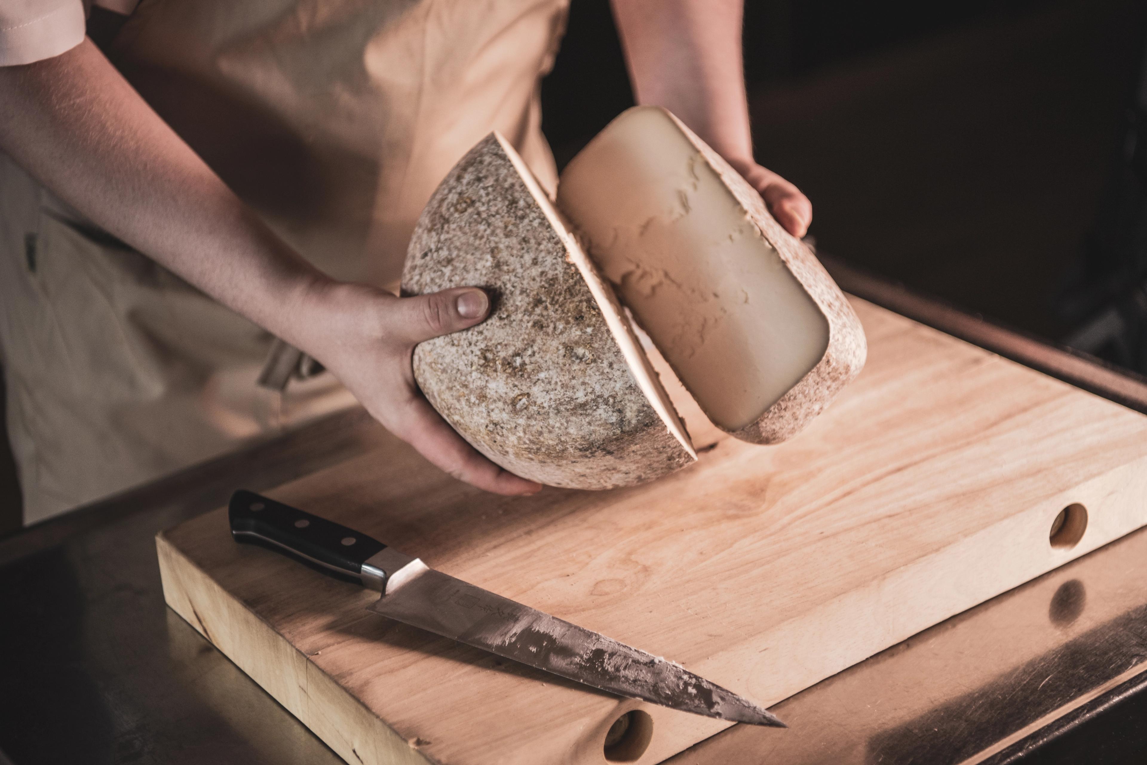 To hender som holder i hver sin halvdel av et ostehjul delt i to.