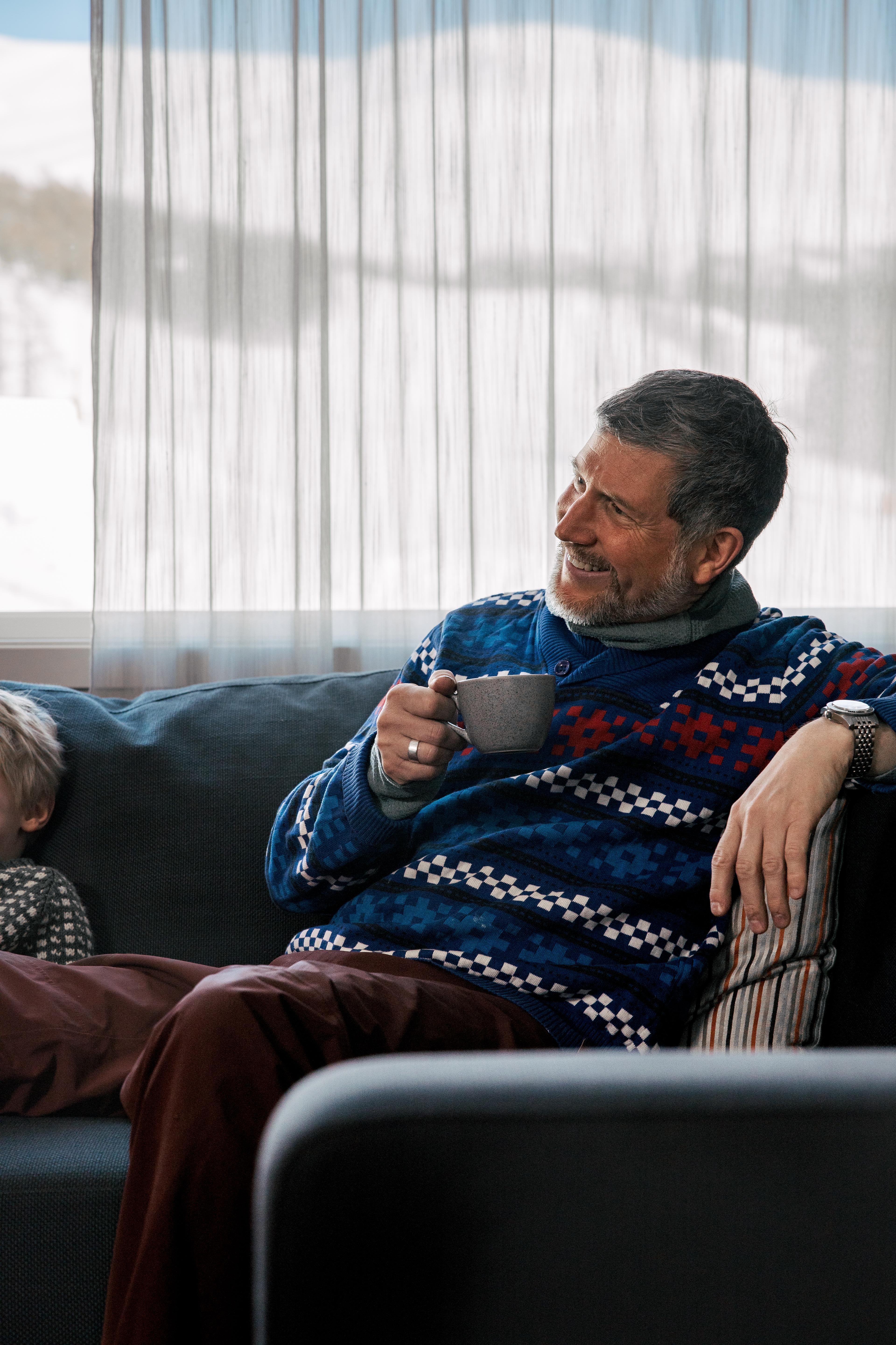 Mann slapper av i sofaen med en kopp kaffe.