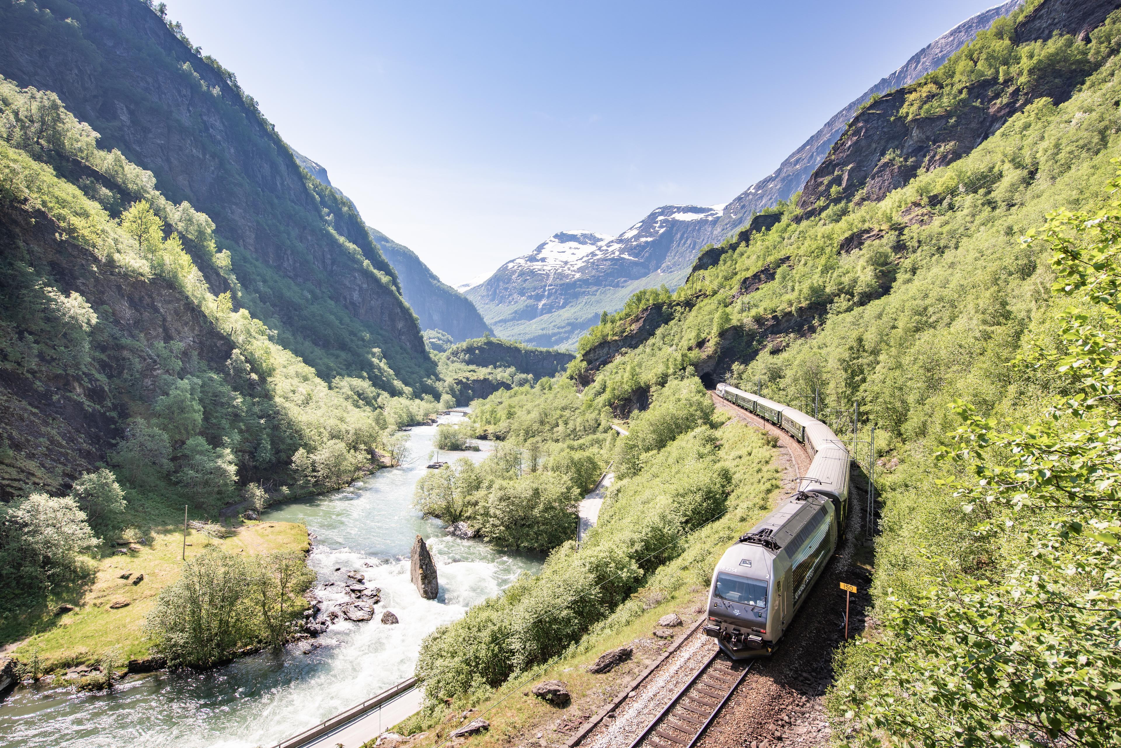 Toget åler seg fram oppover dalen langs med elven en sommerdag.