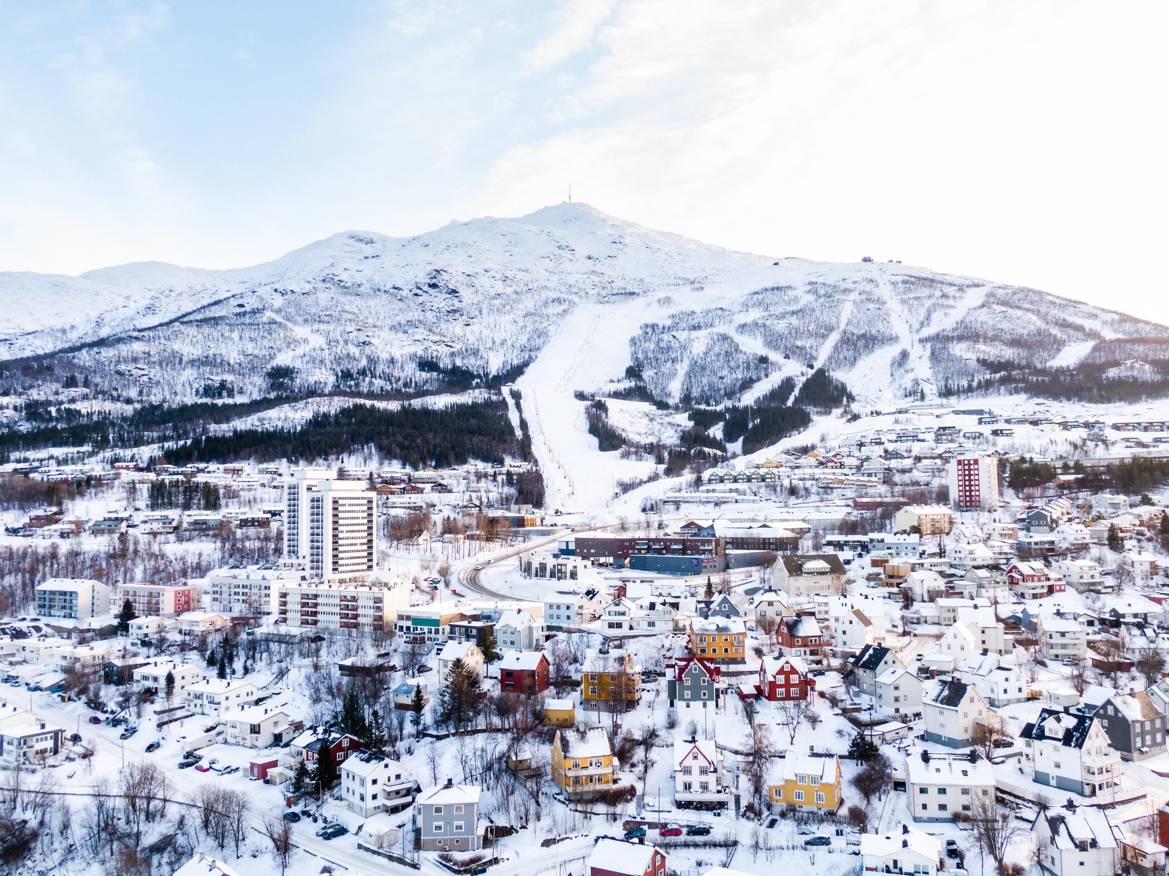 Vue sur Narvik en hiver, avec des bâtiments au premier plan et des montagnes enneigées à l’arrière-plan.