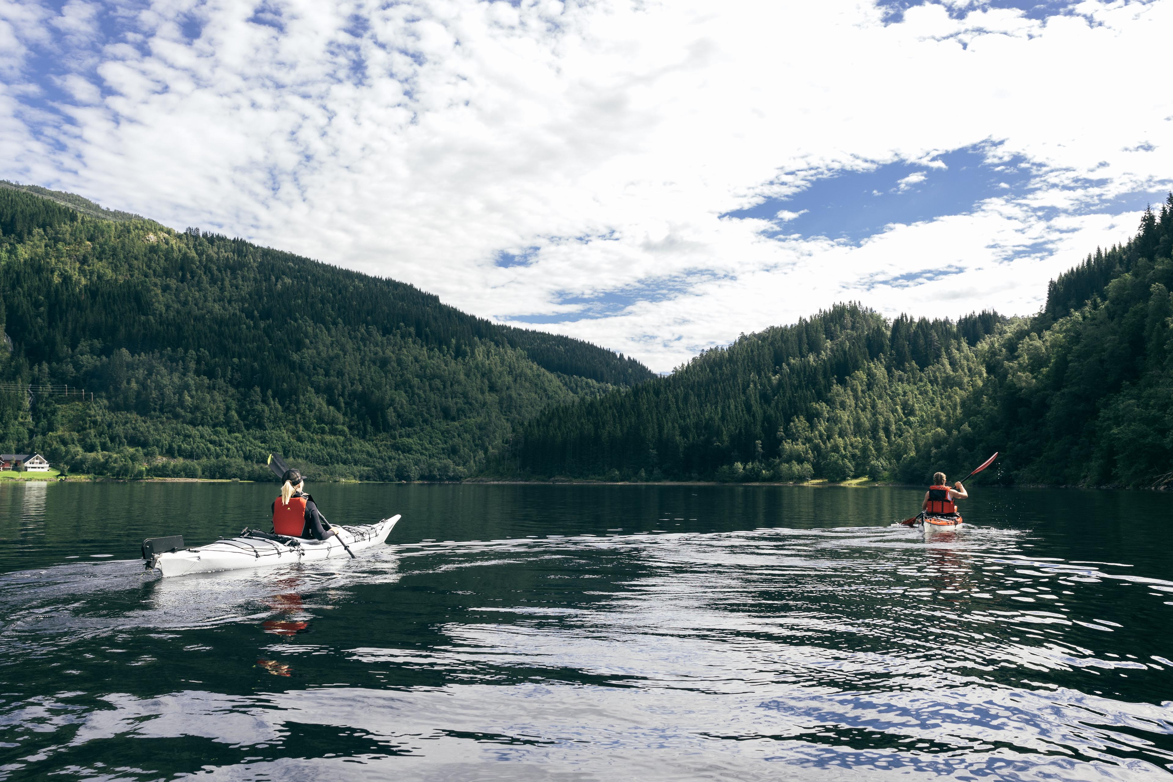 Kajakkpadlarar i havkajakk på vatnet.