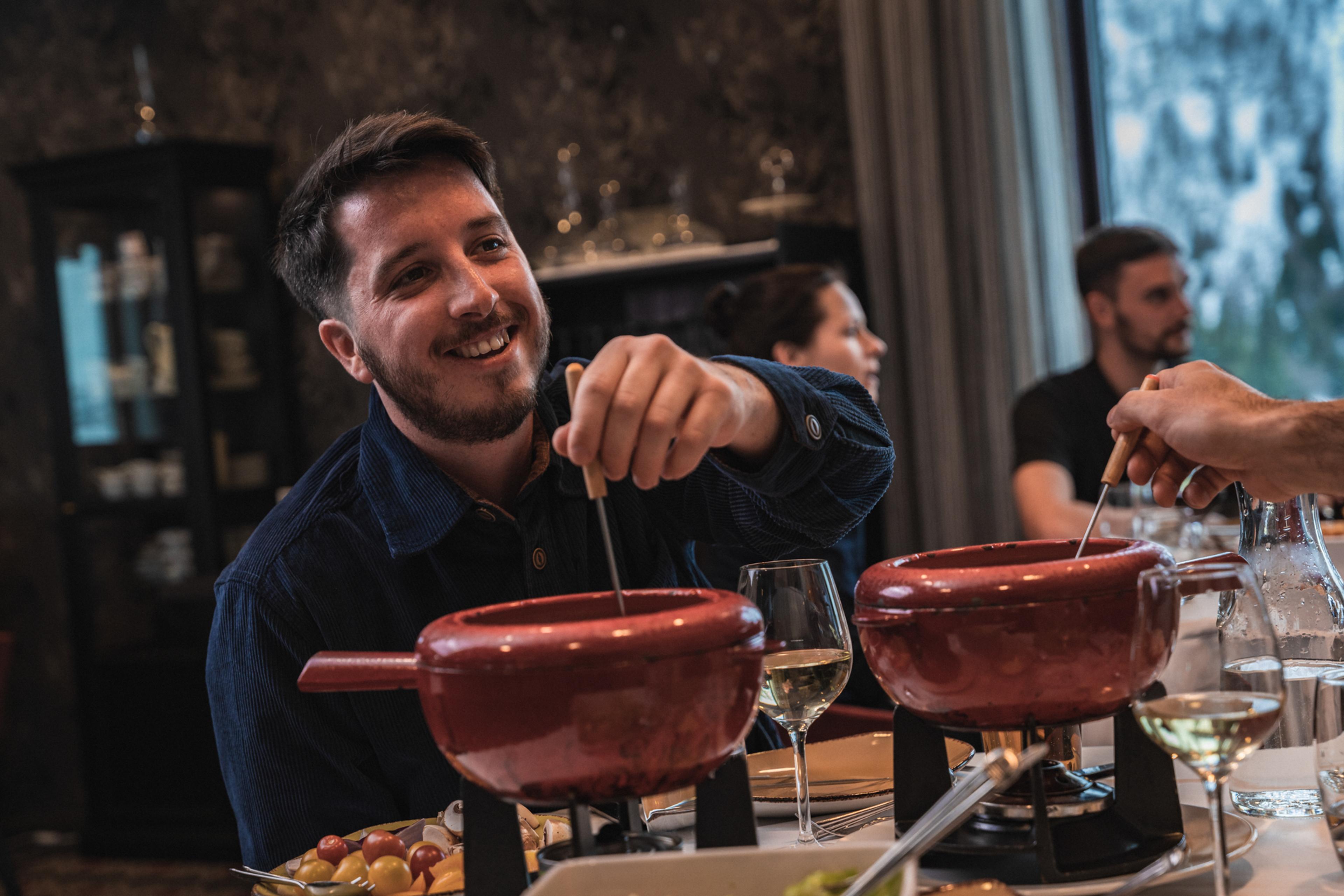 Venner koser seg med fondue og vin på restaurant.