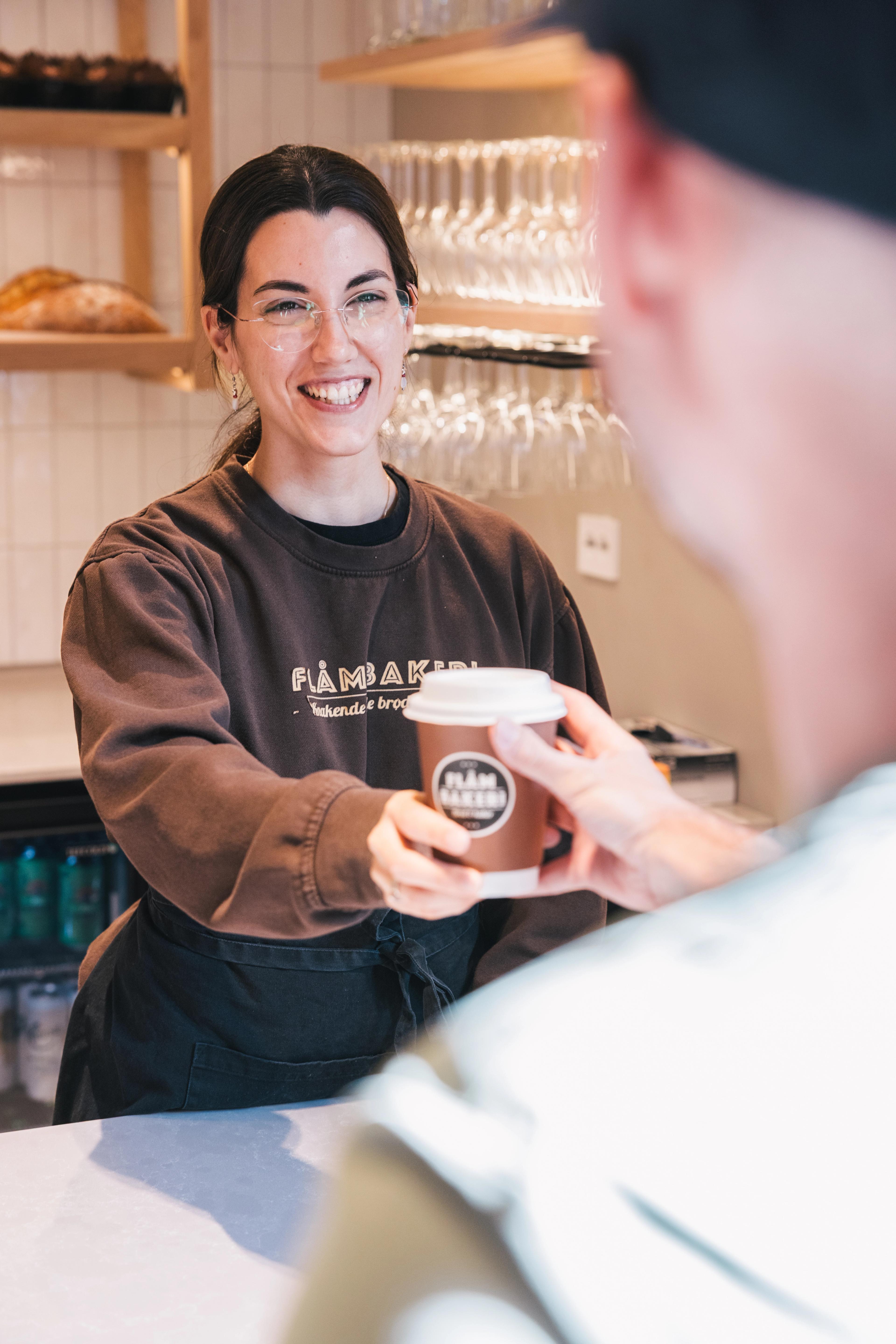 Eine Frau serviert einem Gast in der Flåm Bäckerei Kaffee.