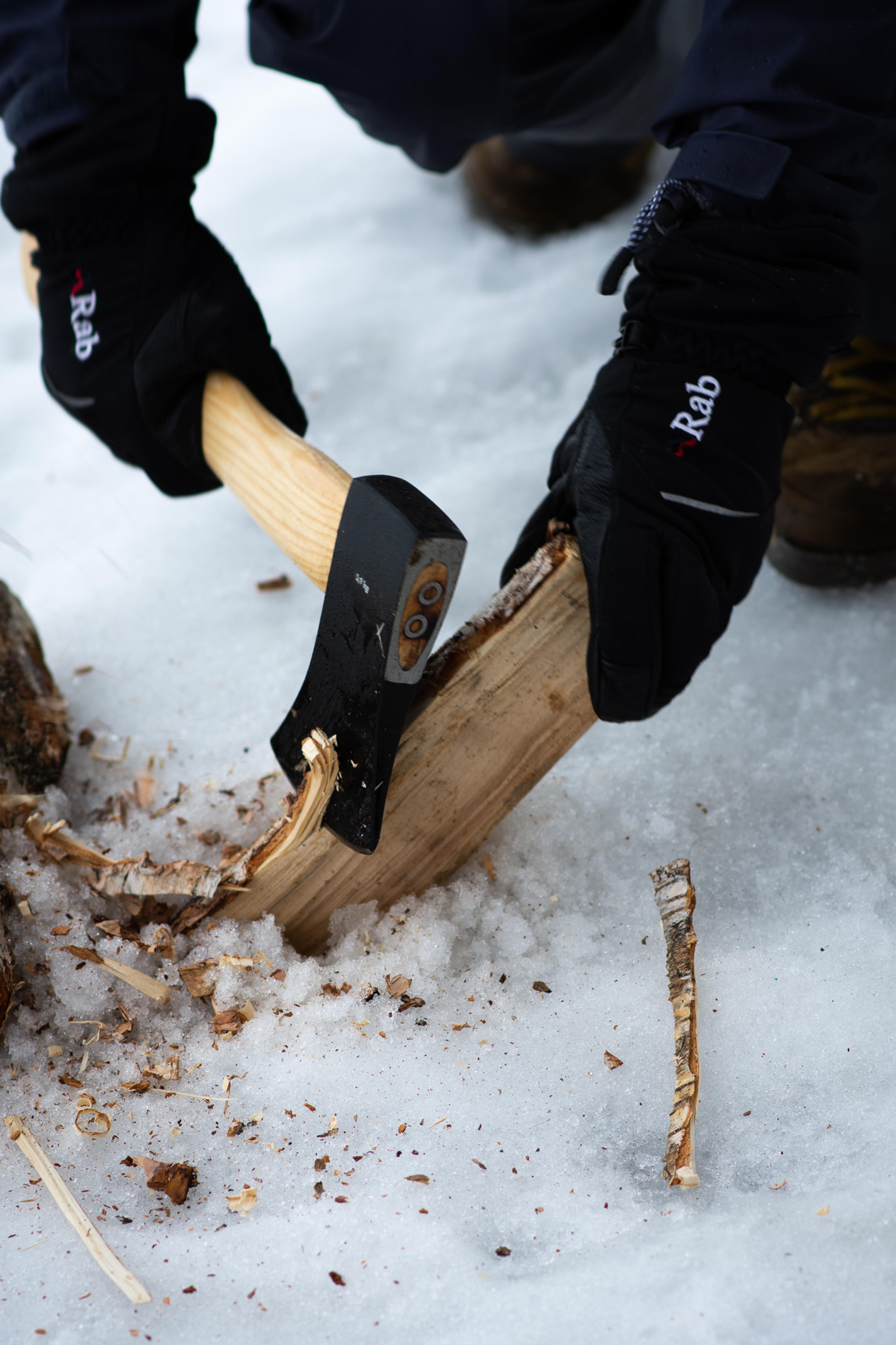 Øks brukes for å hugge opptenningsflis av en trekubbe i snøen.