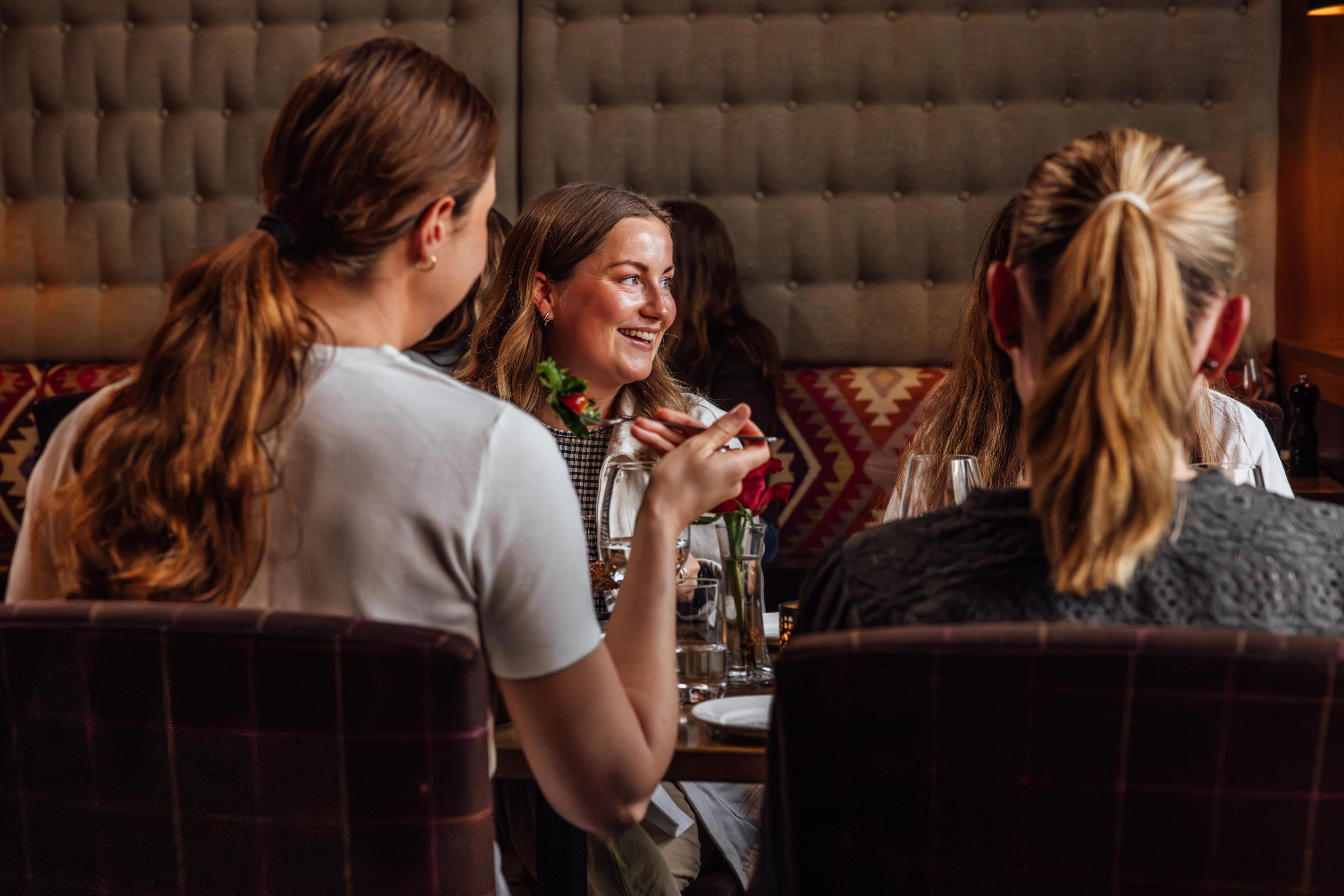 Three women sitting at a restaurant having a good time.