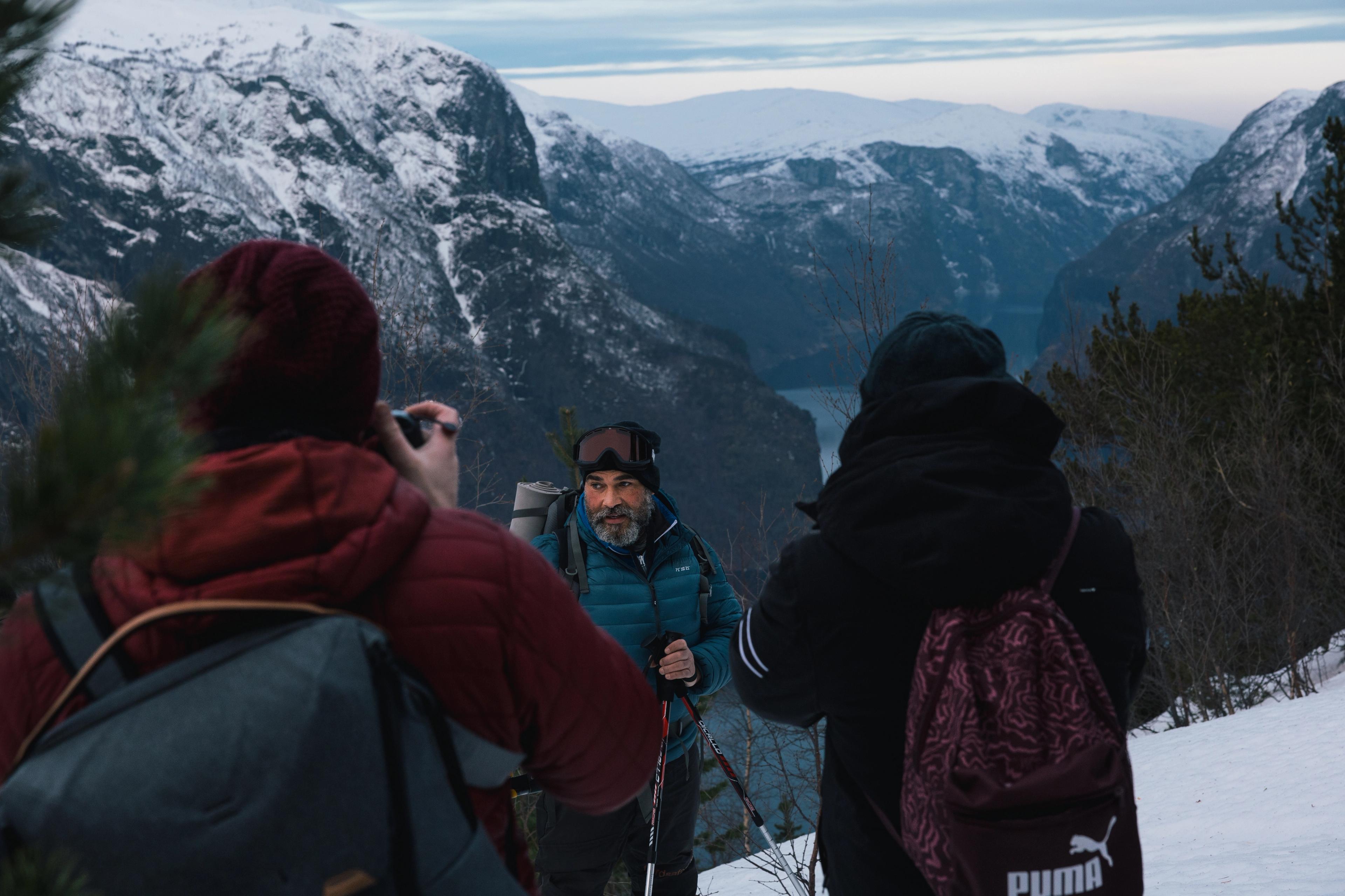 A snowshoeing guide talks to a group of guests on the mountainside above the Aurlandsfjord.