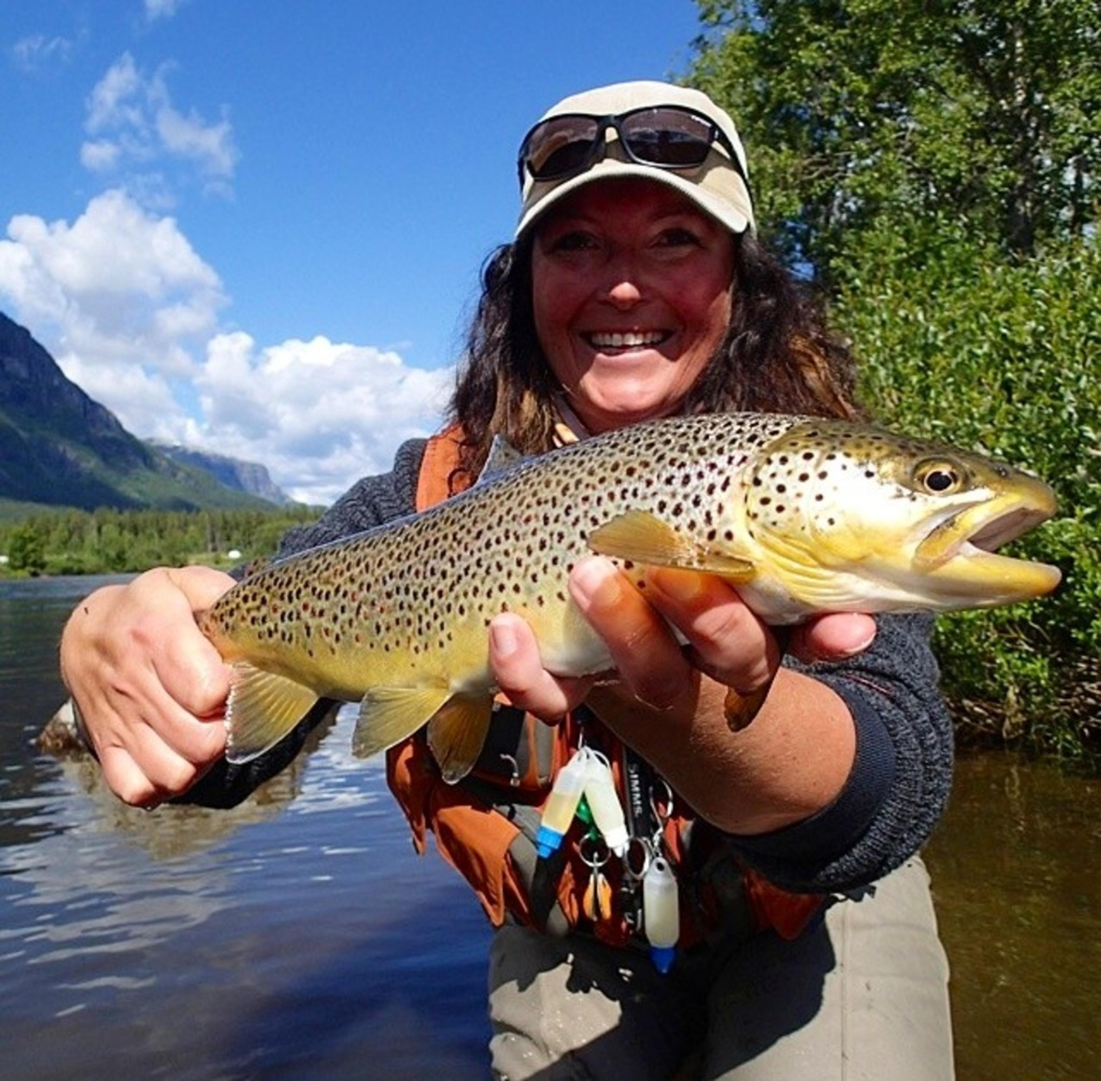 Kvinne holder stolt frem den store ørreten hun har fanget på fjellet.