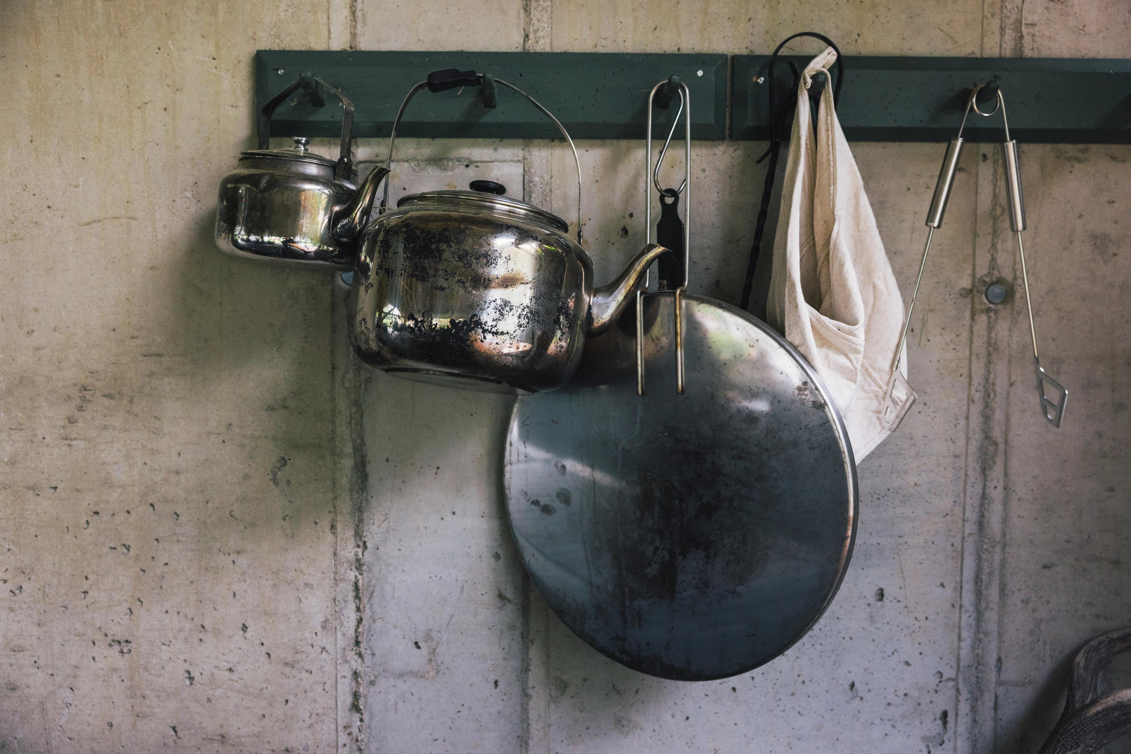 Kjøkkenredskaper i tinn henger på knagger på veggen.