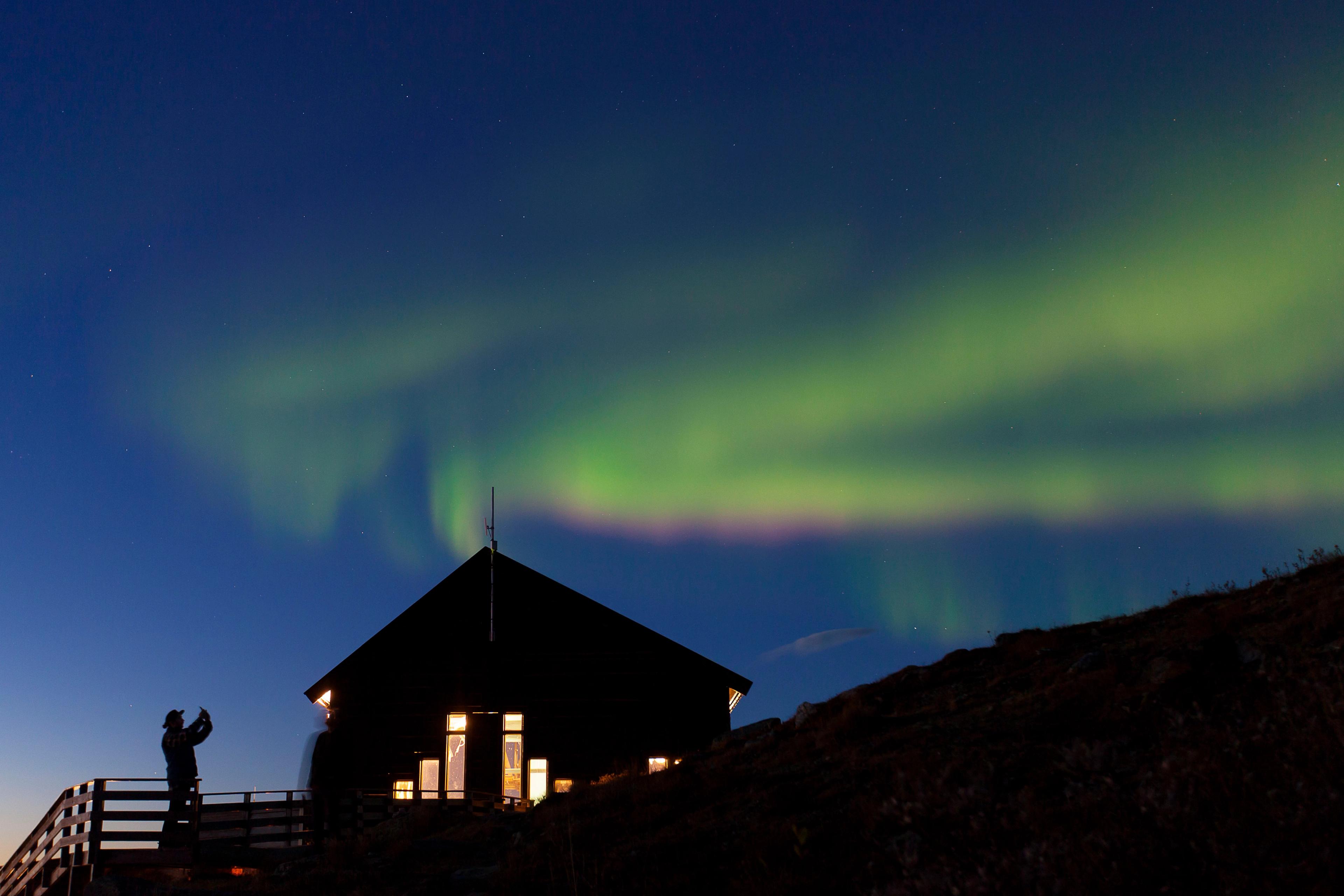 A person taking a photo of the aurora in the sky above the Fjellheis restaurant.