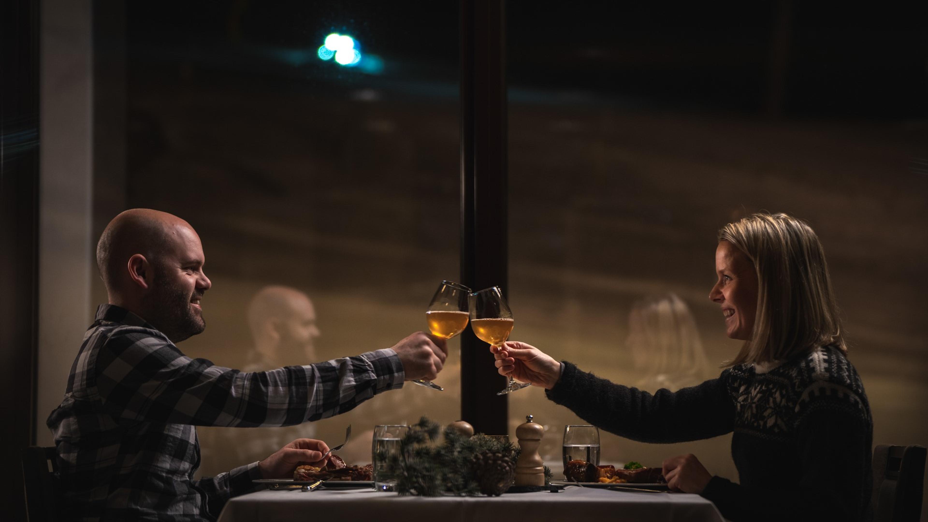 A man and a woman toast across a dinner table at restaurant Nuten at Myrkdalen Hotel.