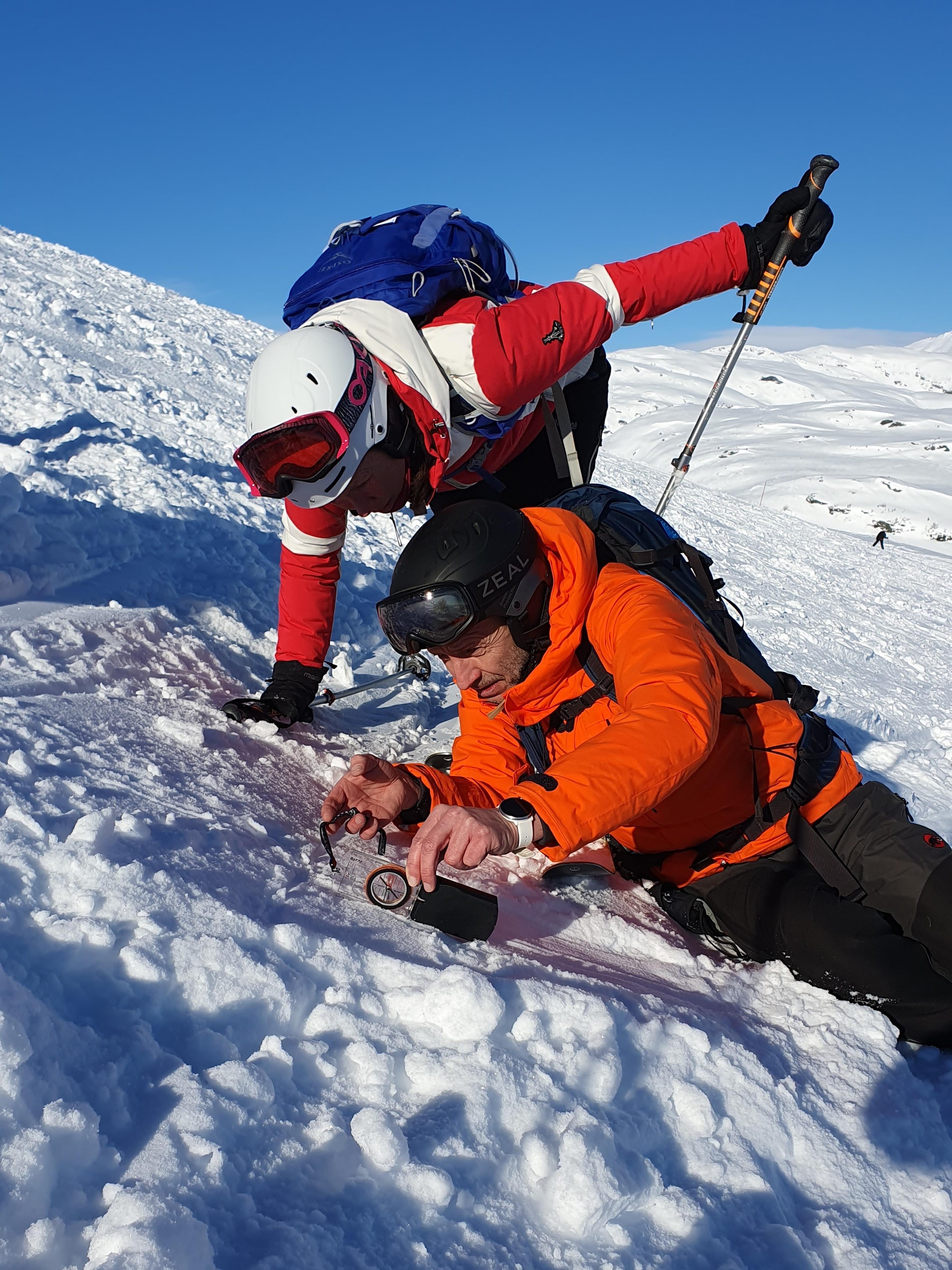 Two people checking the steepness of the terrain during a ski tour