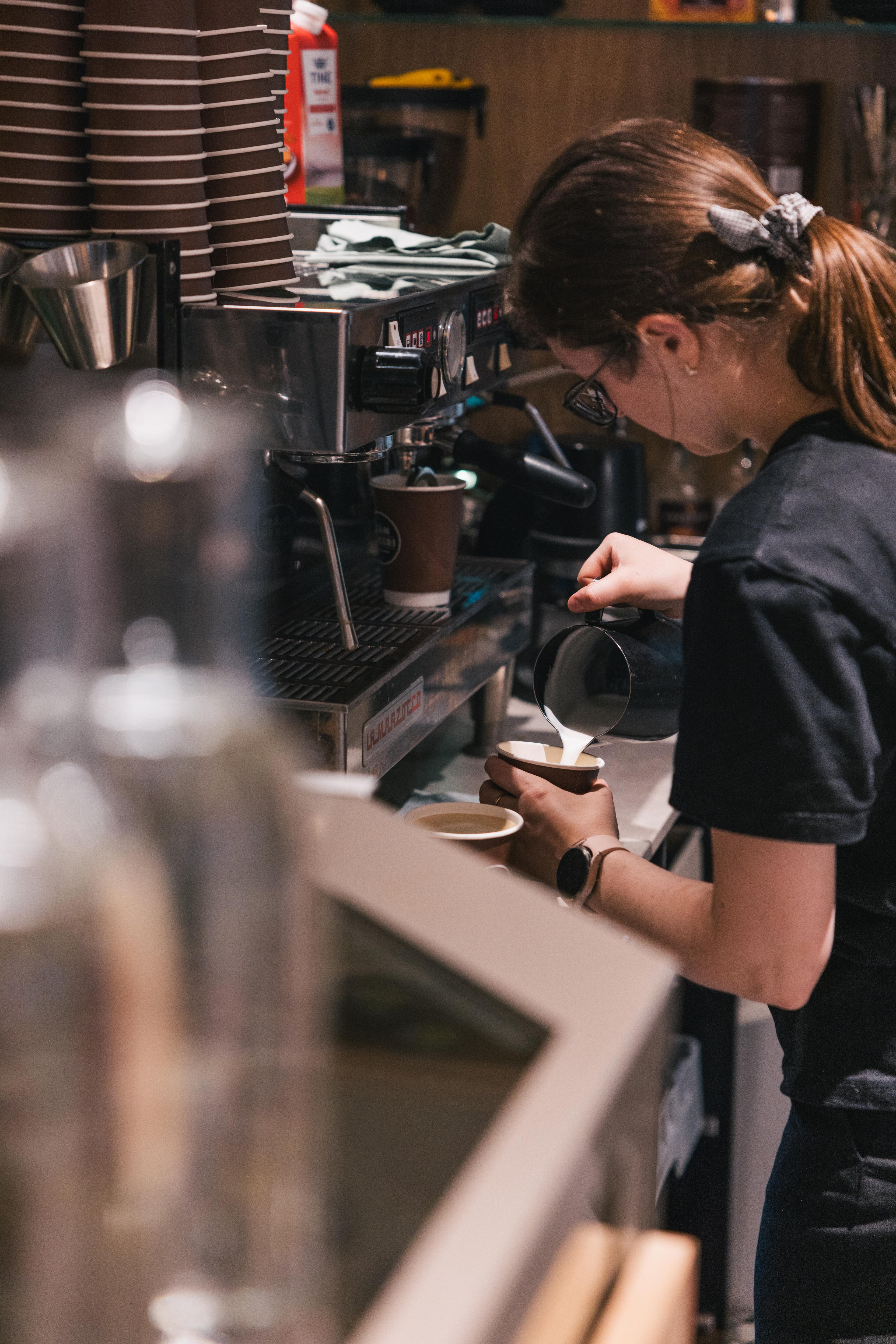 Ein Mitarbeiter der Flåm Bäckerei kocht Kaffee an einer Kaffeemaschine.