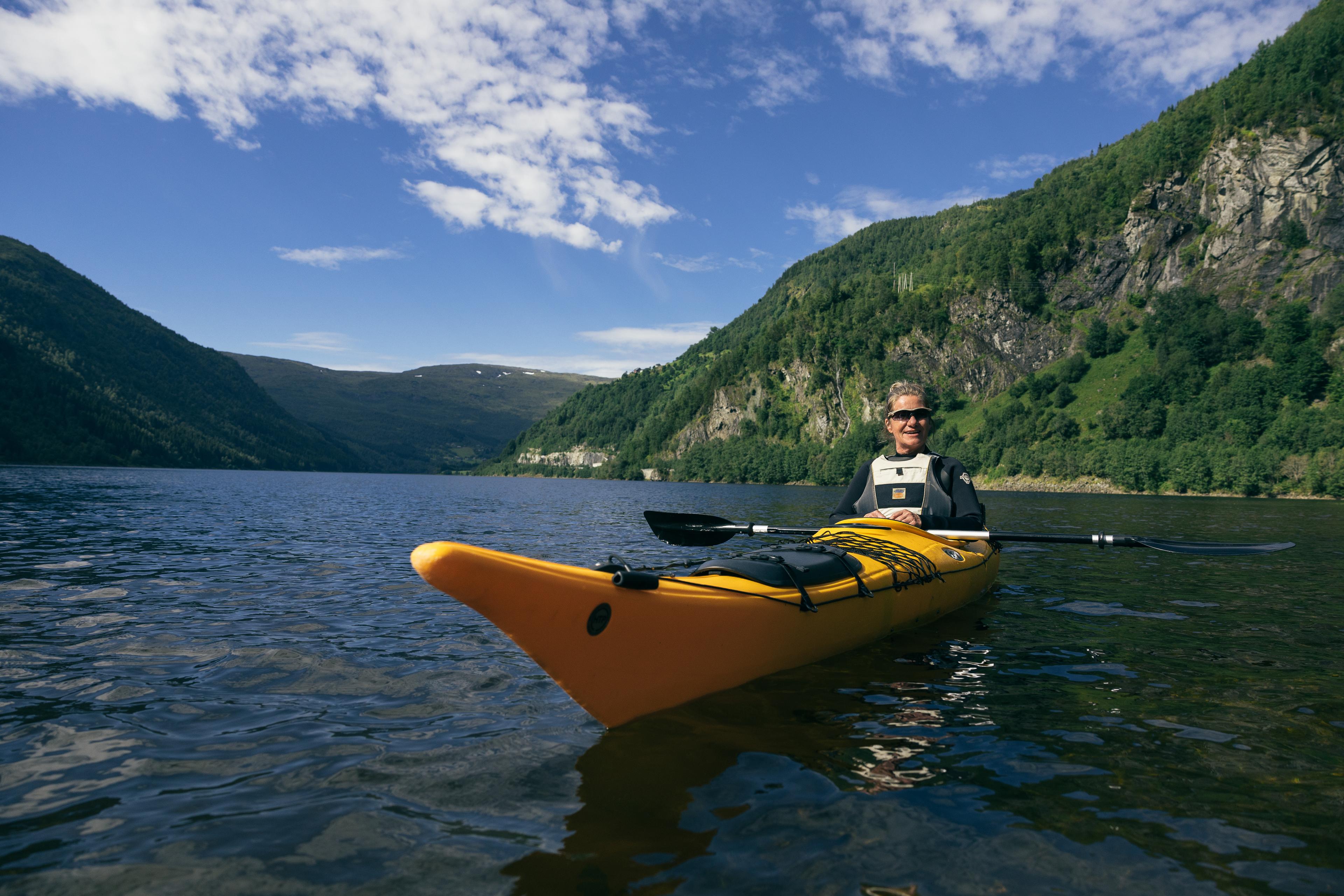 Kvinne padler kajakk i fint vær.