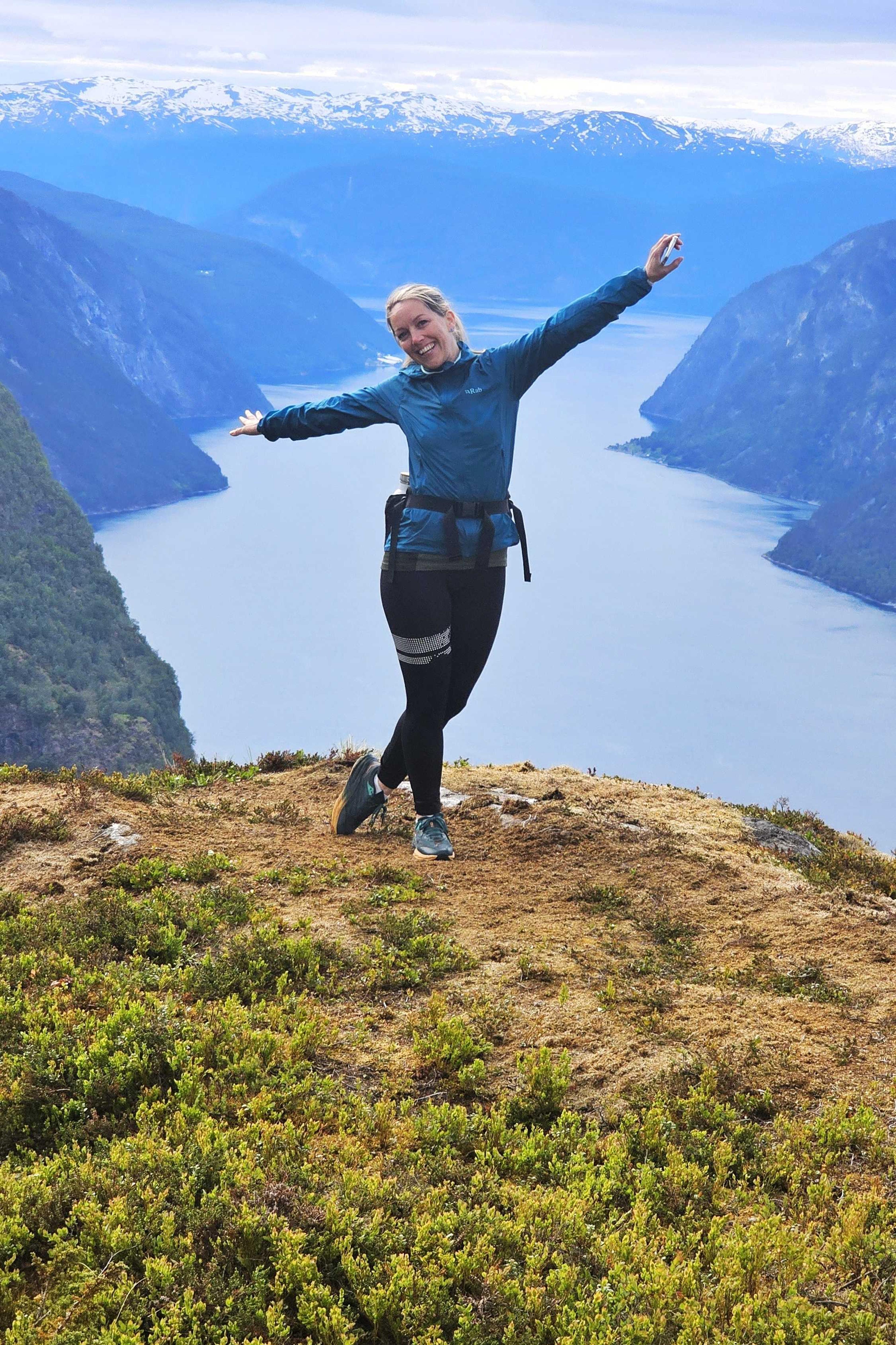  Eine Frau posiert vor einer Aussichtsplattform am Aurlandsfjord.