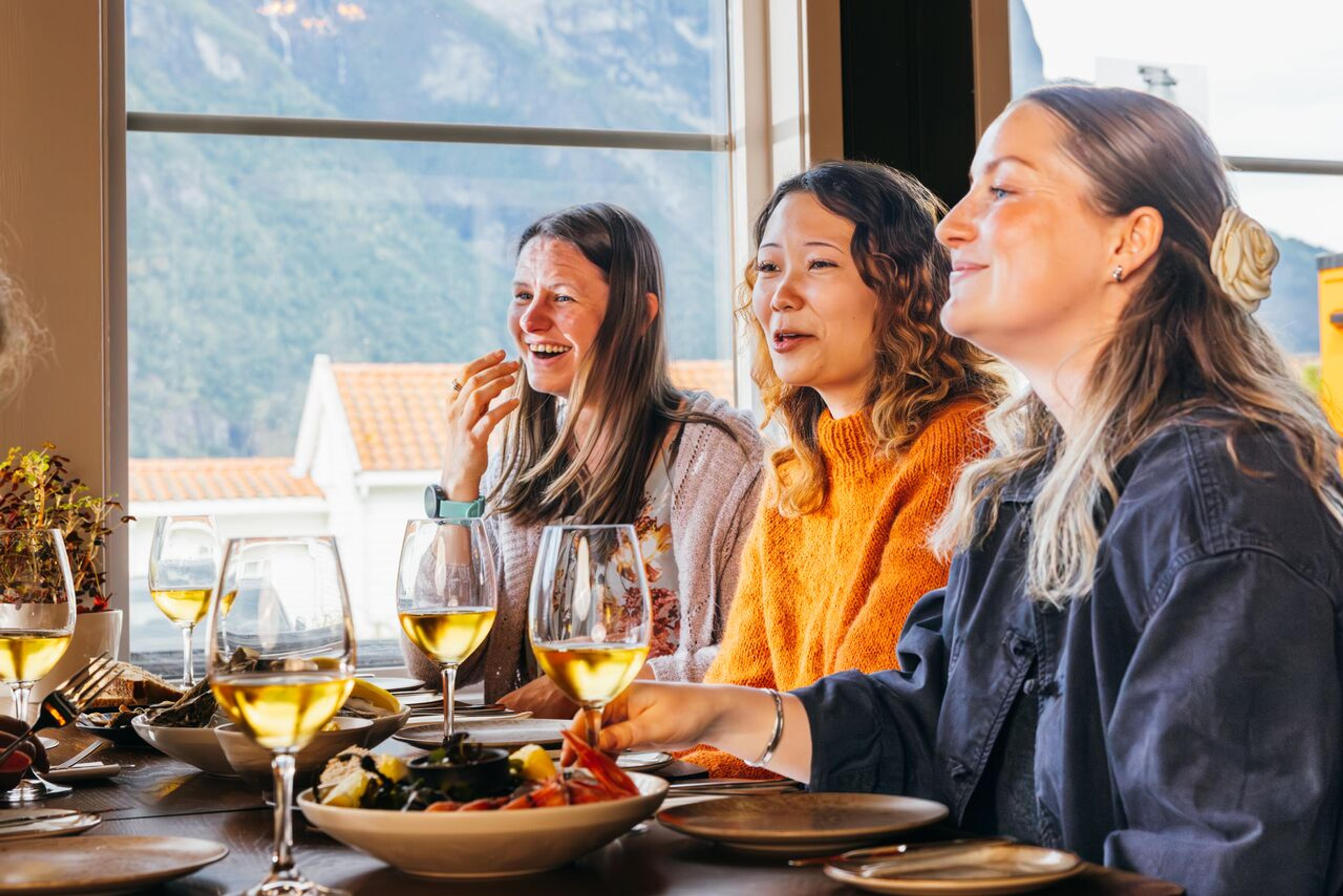 Three women sitting at a restaurant table, laughing.