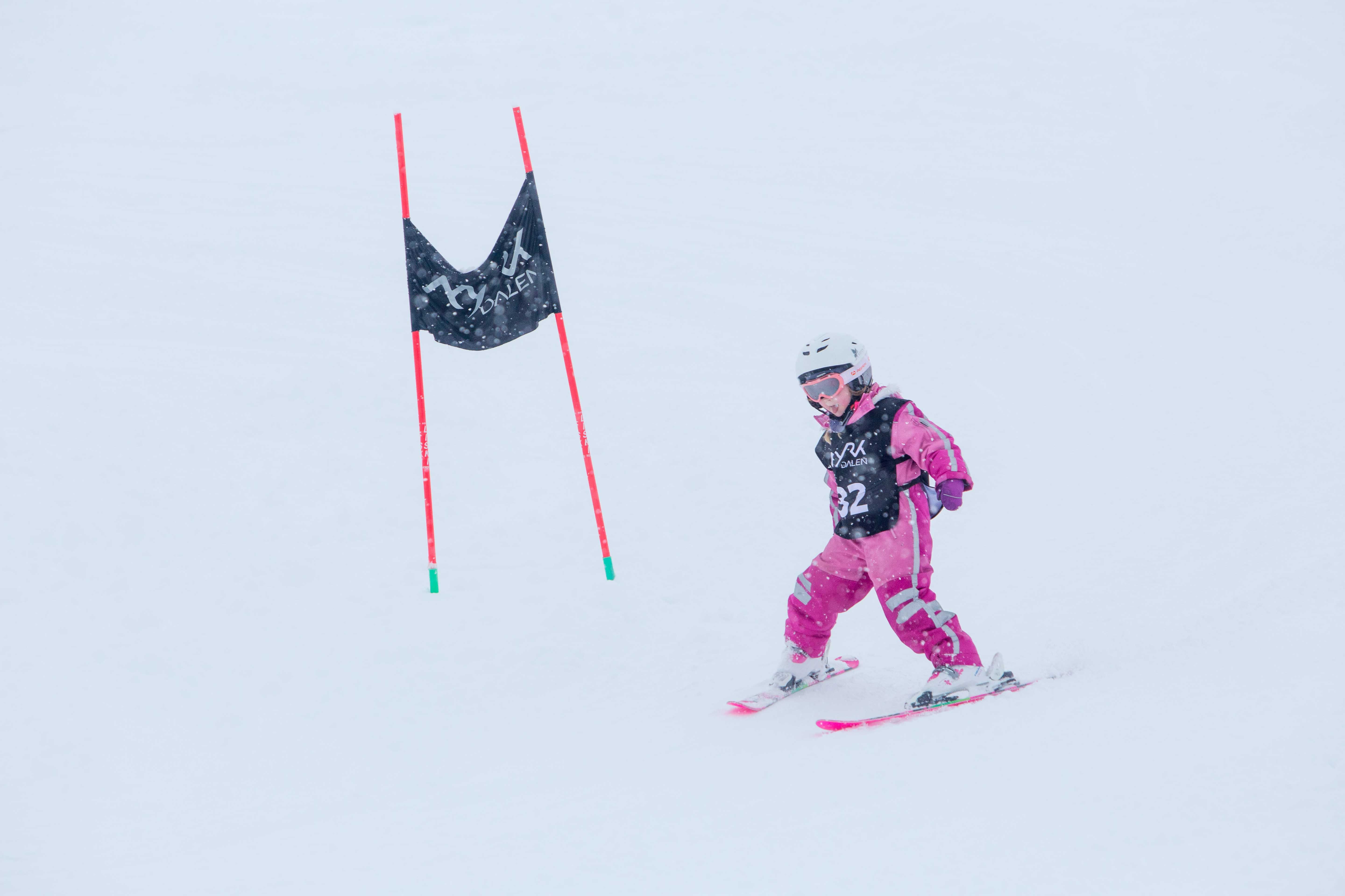 Jente i rosa skiklede på veg nedover skibakken