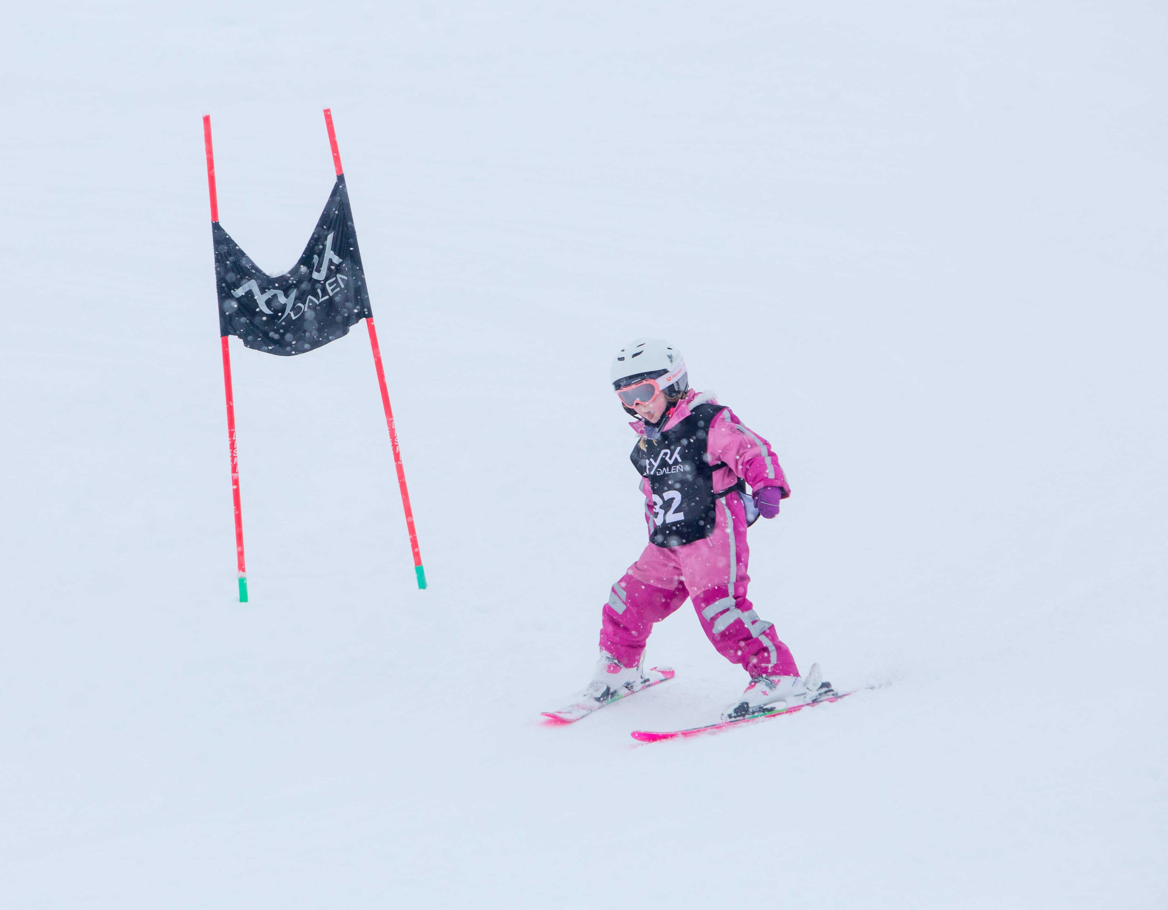 Girl in pink ski gear on her way down the ski slope.