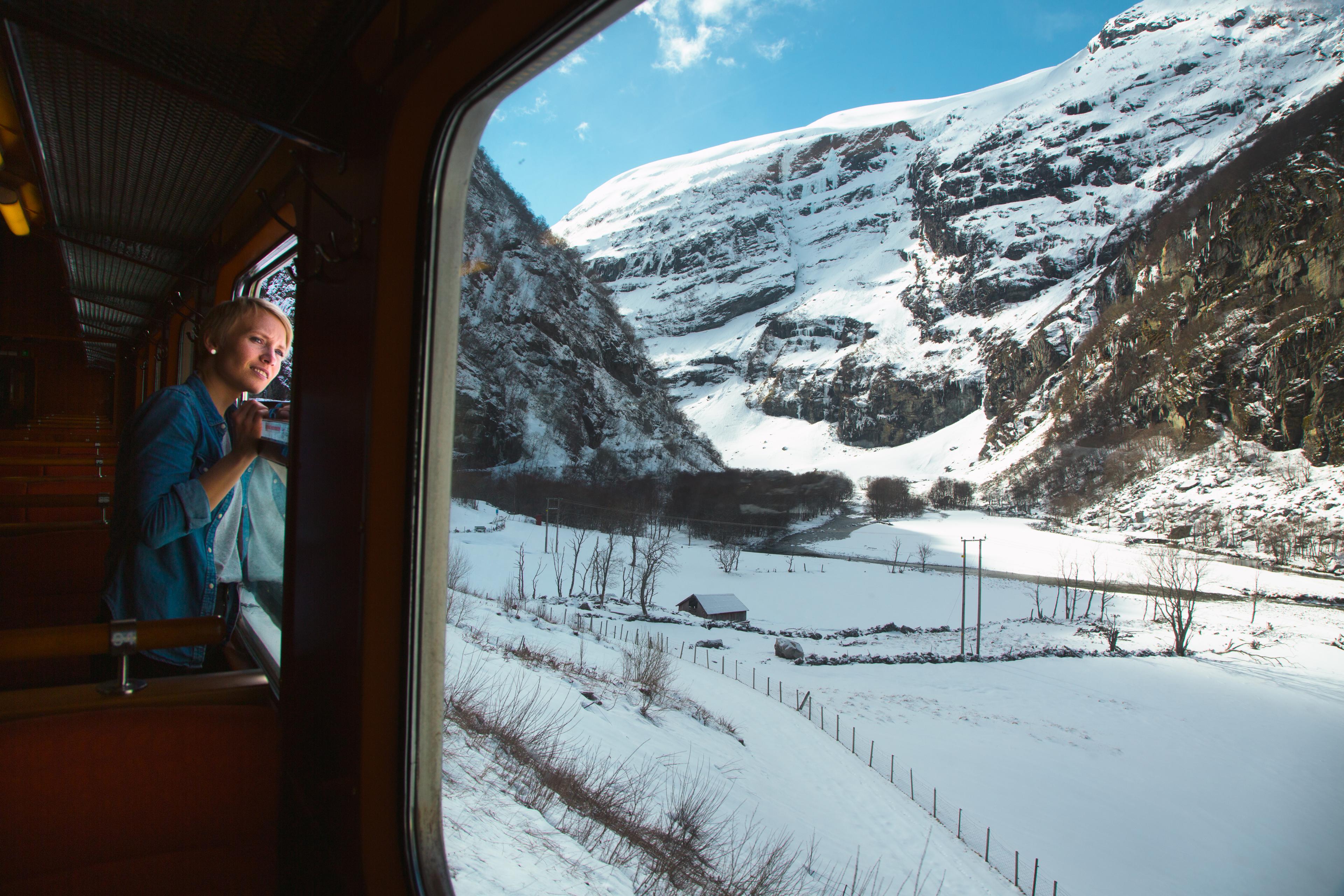 Kvinne kikker ut av togvinduet utover en snødekket dal.