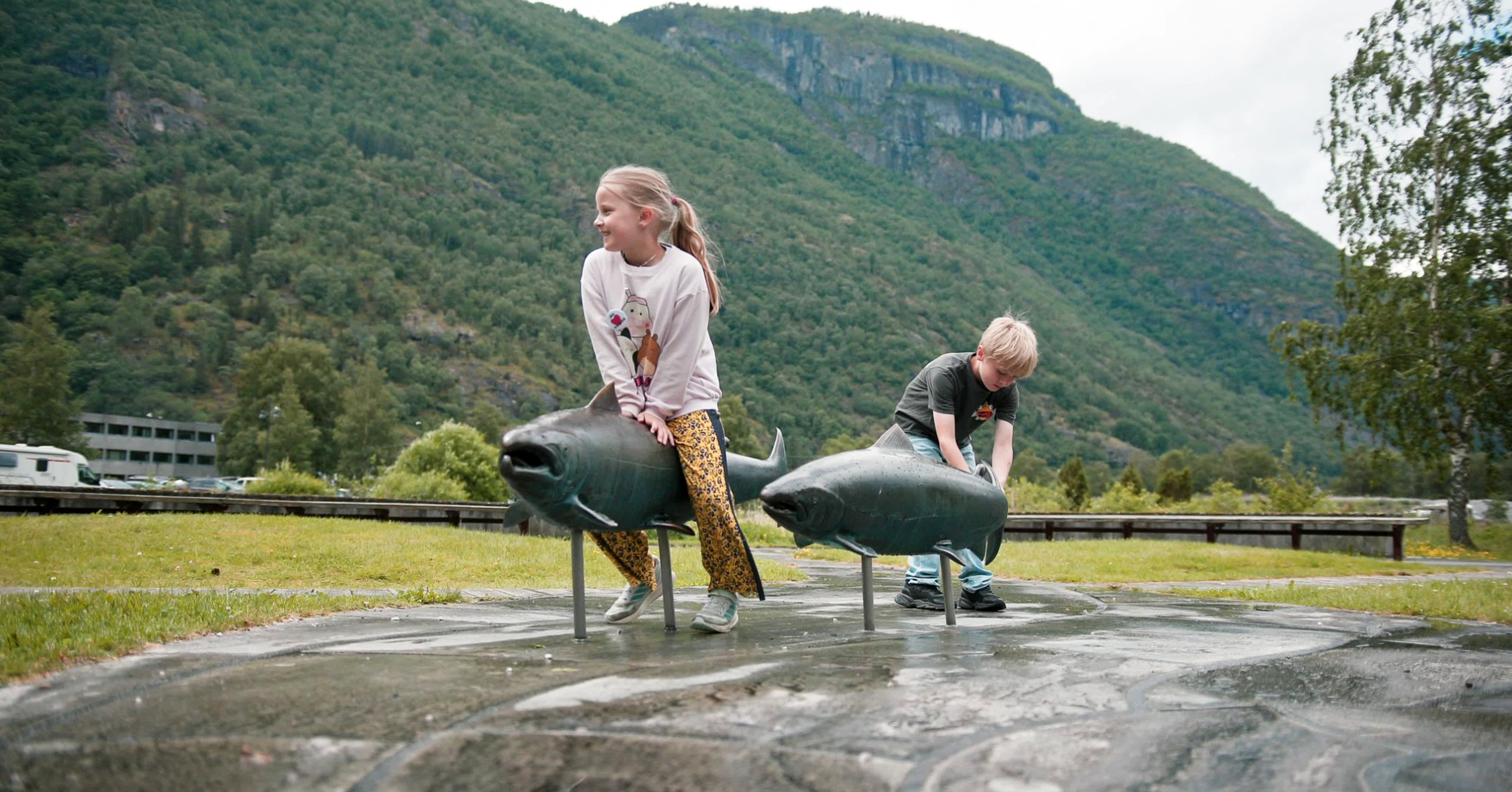 Children playing at a installation of salmon made in steel.