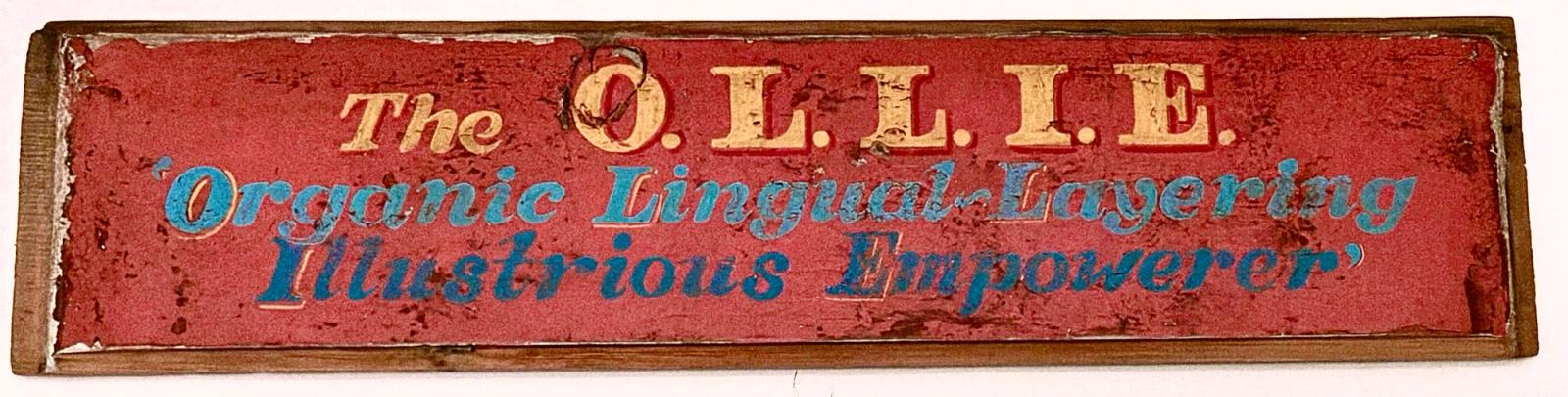 Hand-painted O.L.L.I.E. sign reading “Organic Lingual-Layering Illustrious Empowerer”, given to Stephen by Kate Bush.