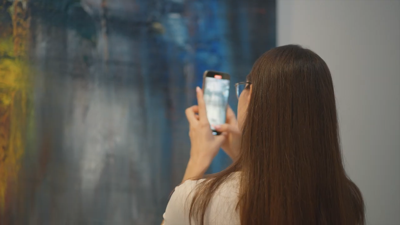 A visitor photographing a painting by Rima Chahine at Almaz, Andakulova Gallery