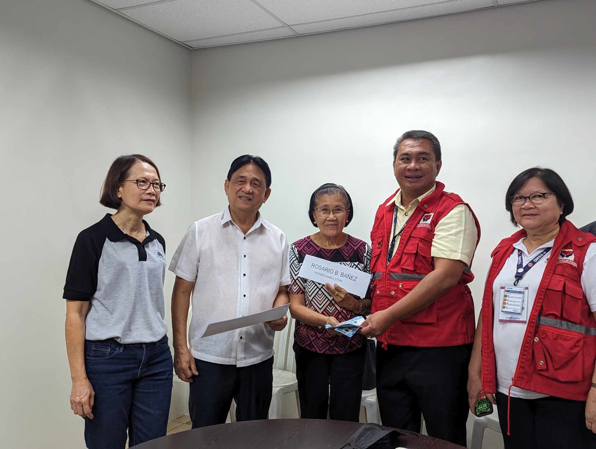 RICE SUBSIDY. Rosario B. Bañez, a rice retailer (center) in Iloilo City, receives his P15,000 subsidy during the initial payout at the Office of Vice Mayor Jeffrey Ganzon last September 13. Also in the photo, the Department of Social Welfare and Development Regional Director Lawyer Carmelo Nochete. (Photo courtesy of DSWD)