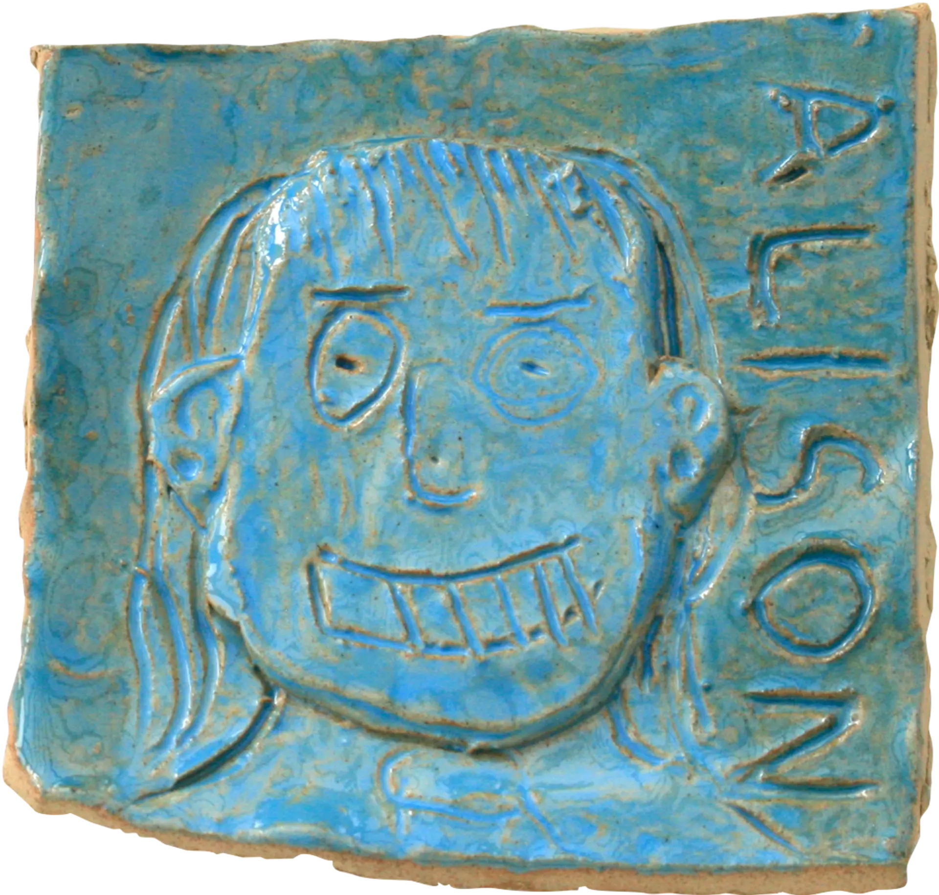 A blue glazed ceramic tile of Alison, a member of the Montrose group's mum. Her name is written down the right hand side of the tile. She is smiling. 