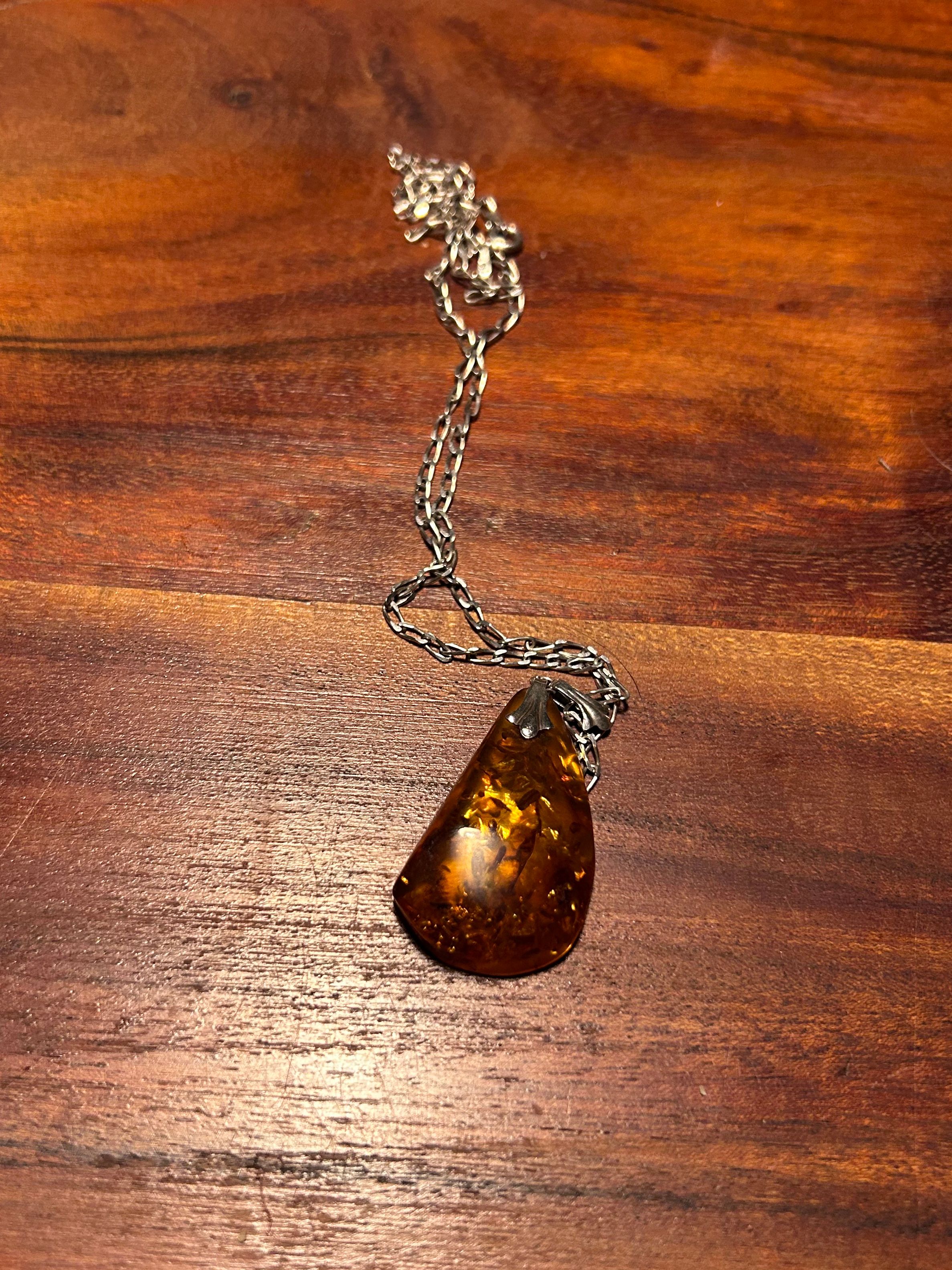 Tear-shapes of amber amulet on silver chain.