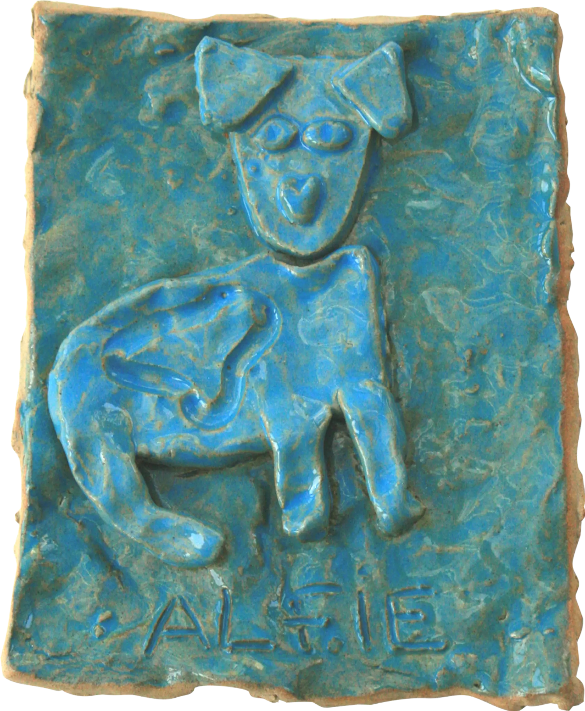 A blue glazed ceramic tile of Alfie, Clair’s pet dog. His name is written along the bottom of the tile.