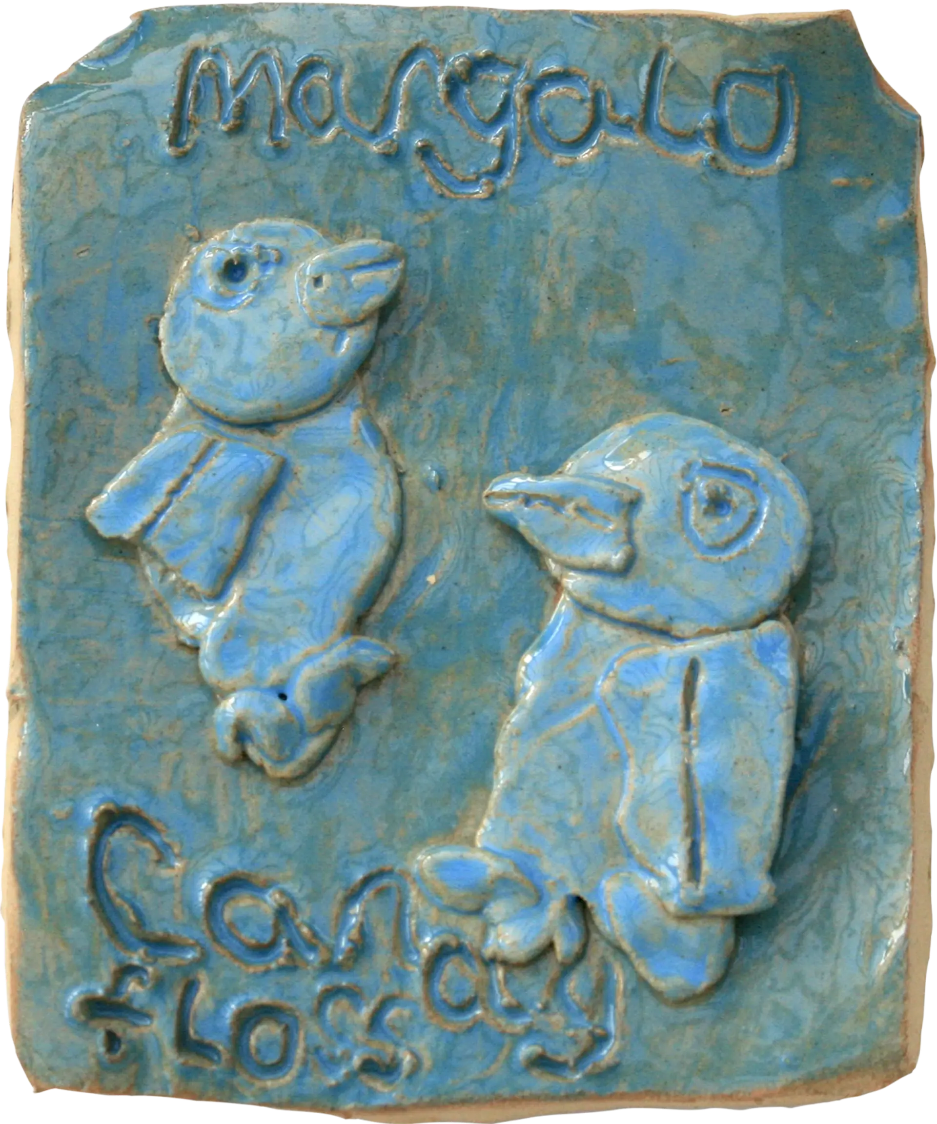 A blue glazed ceramic tile of Jessica’s canaries, their names ‘Margolo’ and ‘Candyfloss’ are carved into the tile. 
