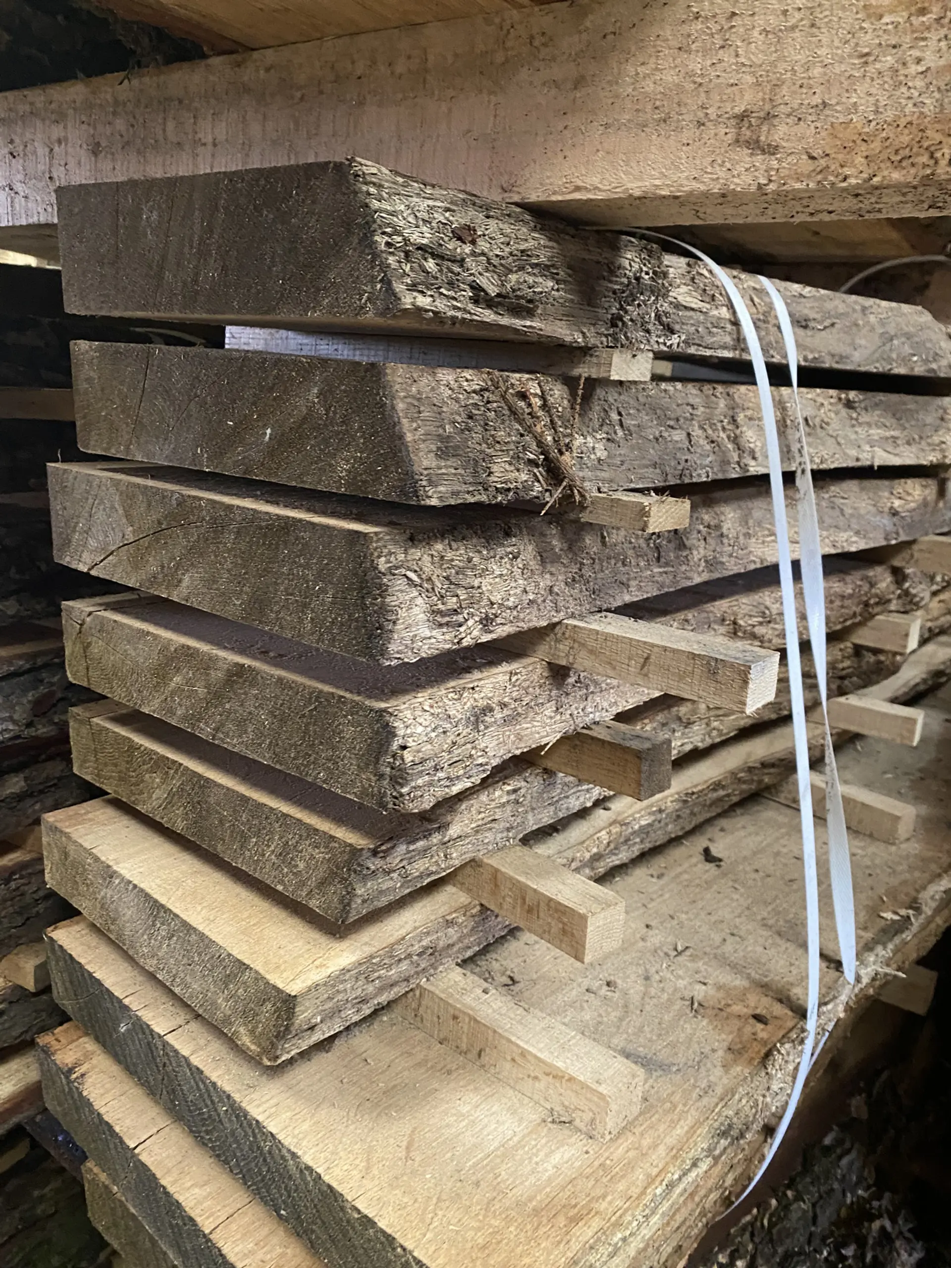 Stacks of unfinished looking wood planks, held apart from each other, with short chunks of a different wood