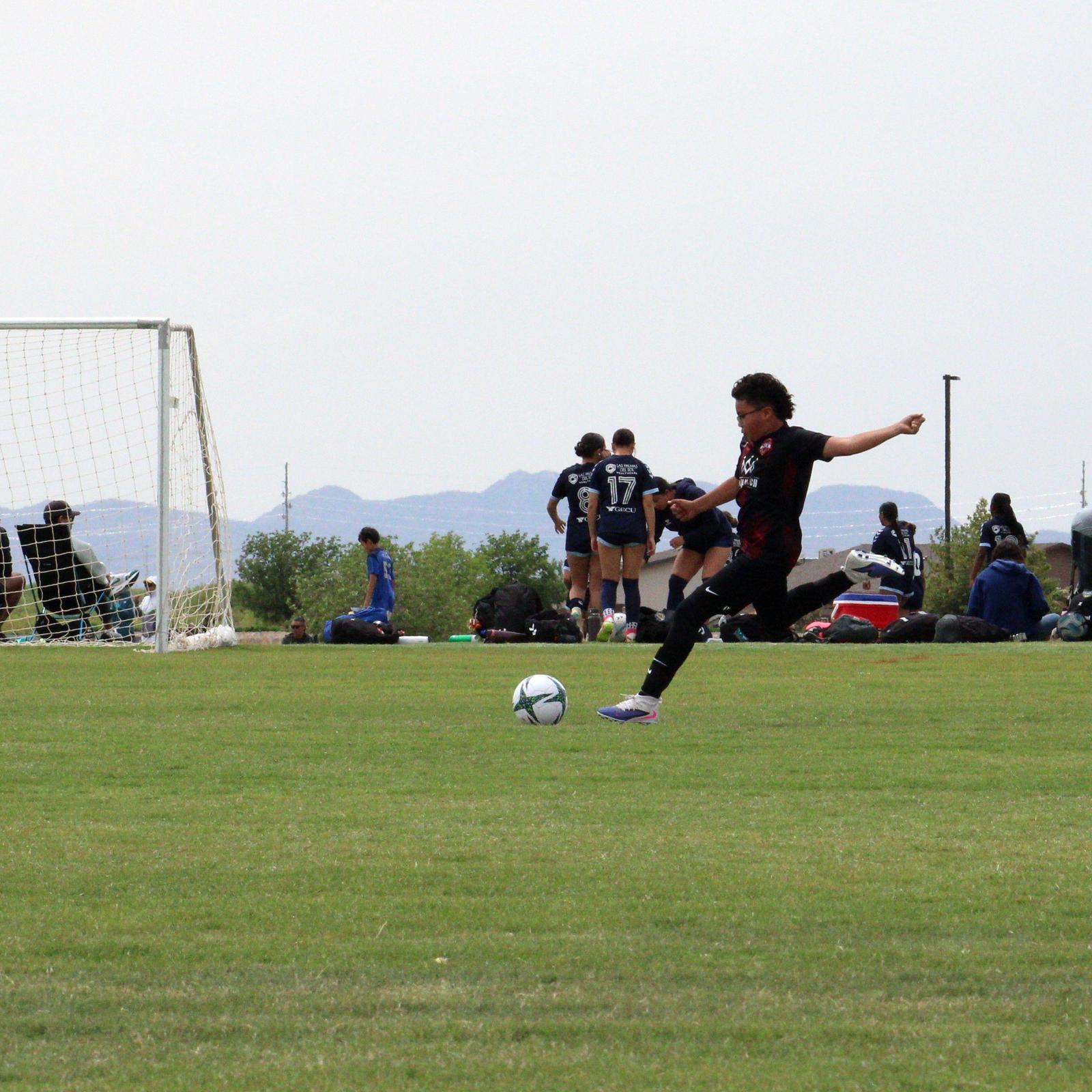 A shot on goal during a Copa de Campeones game, mountains in the distance