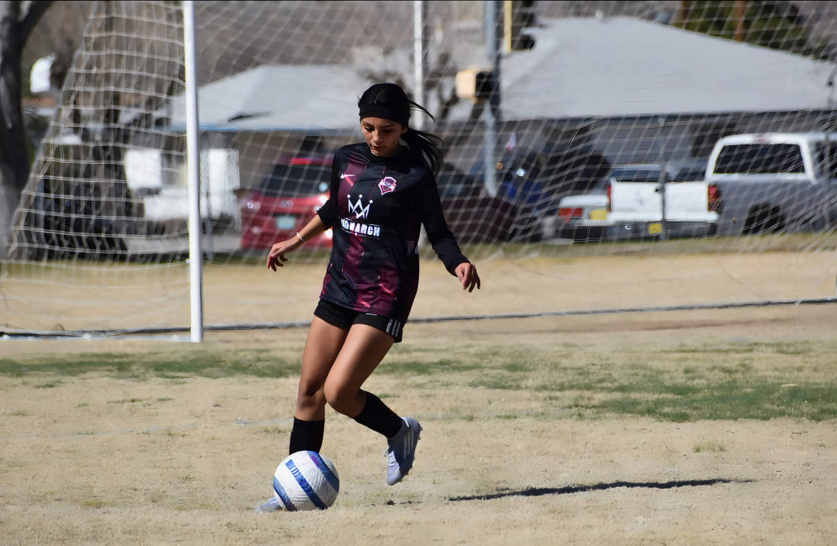 Girls player with the ball in front of goal