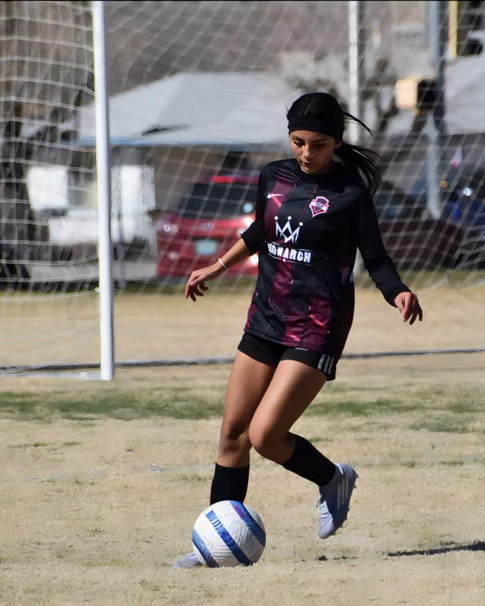 Girls player with the ball in front of goal