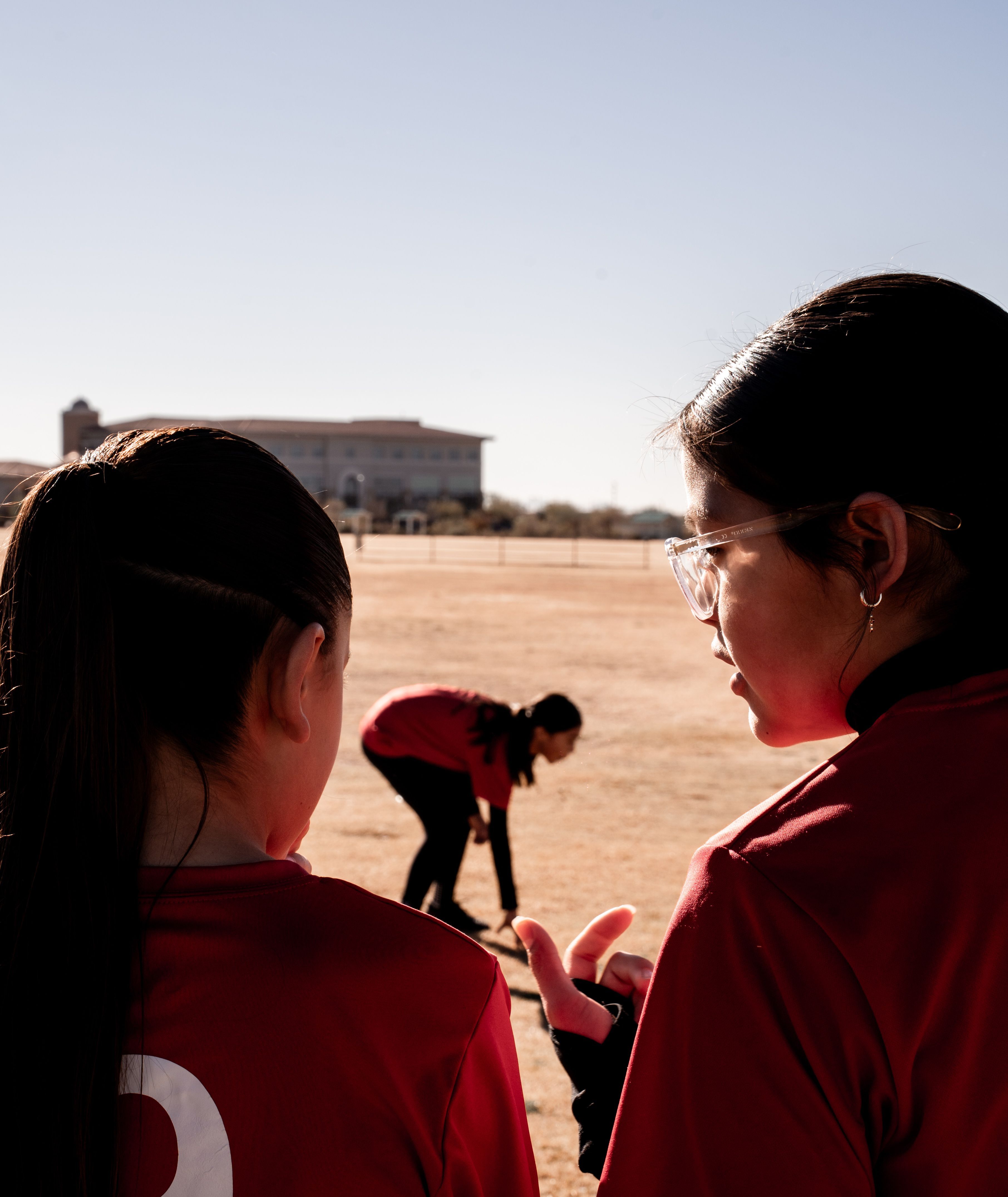 Girls U14 player watching the field at sunset