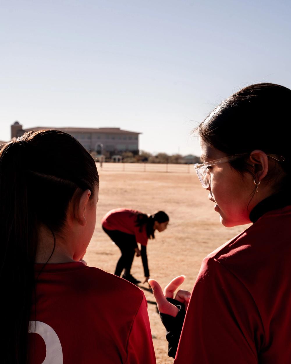 Girls U14 player watching the field at sunset