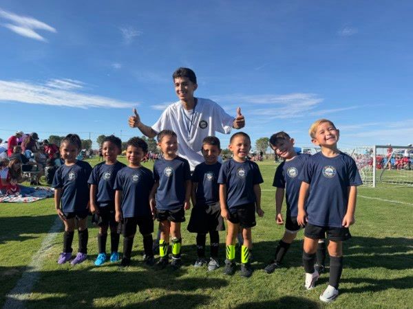 The U5 team lined up with their coach, thumbs up